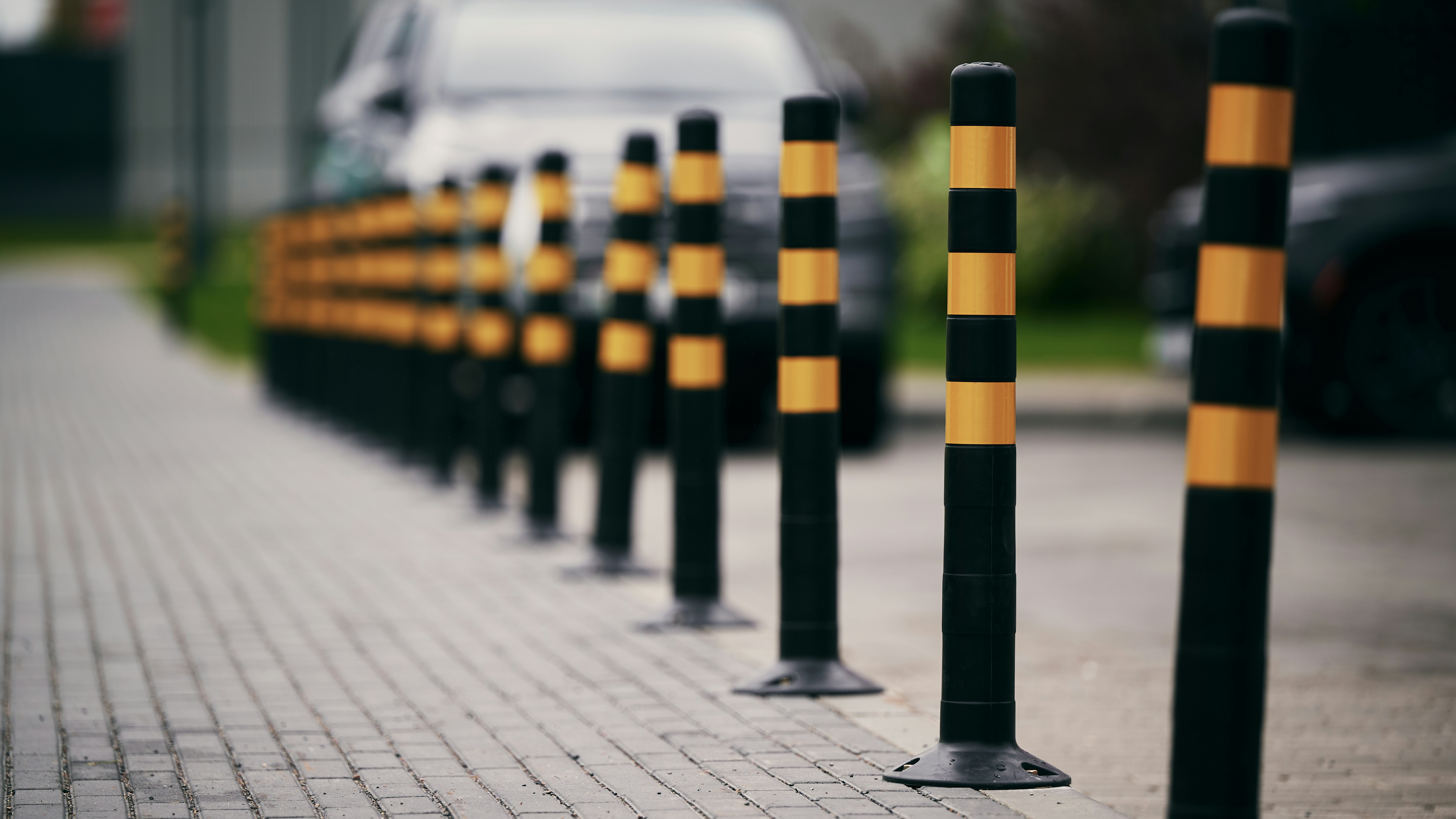 Bolardos pretos e amarelos alinham um caminho pavimentado.
