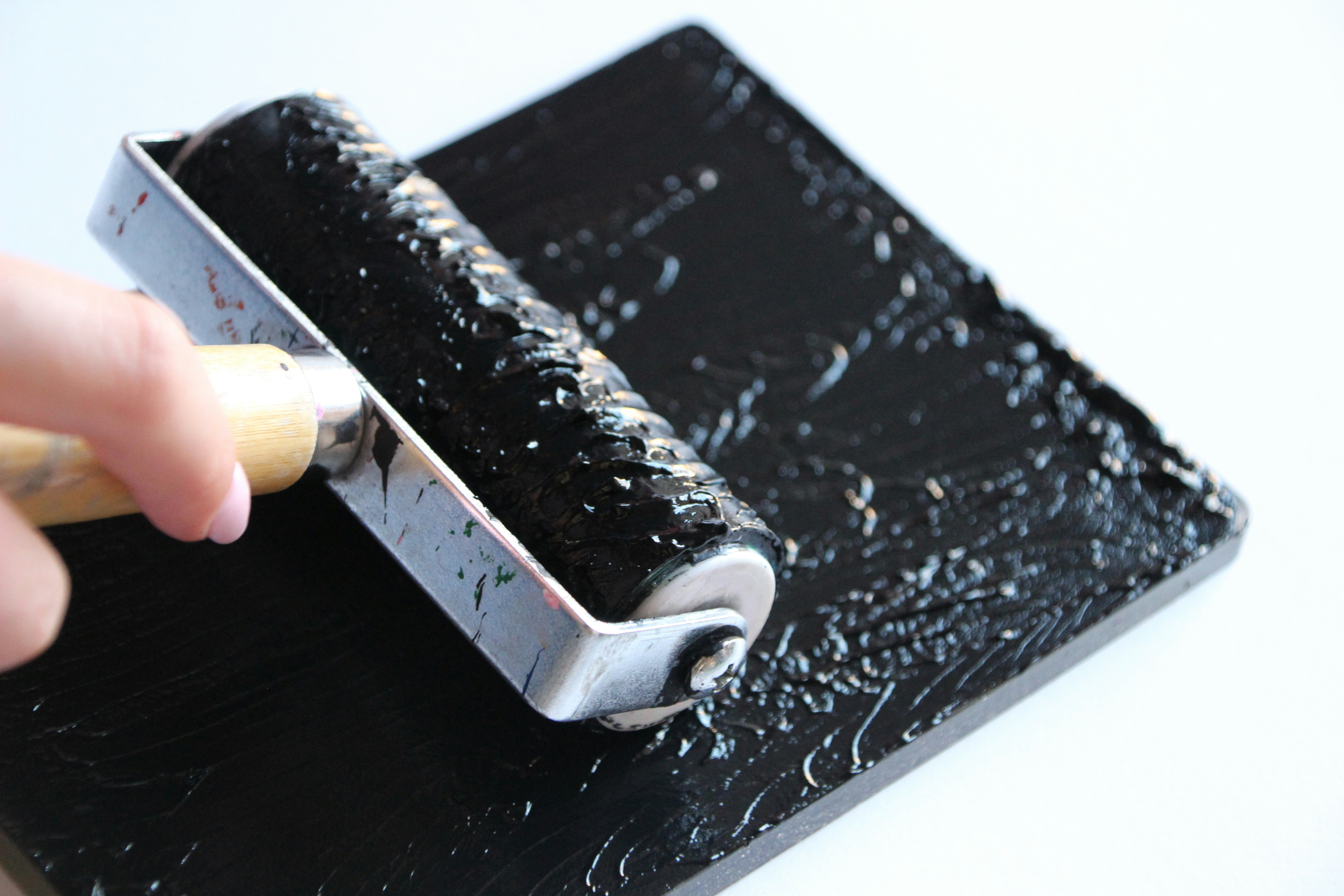 Schwarze Tinte von Hand auf eine Oberfläche rollen.