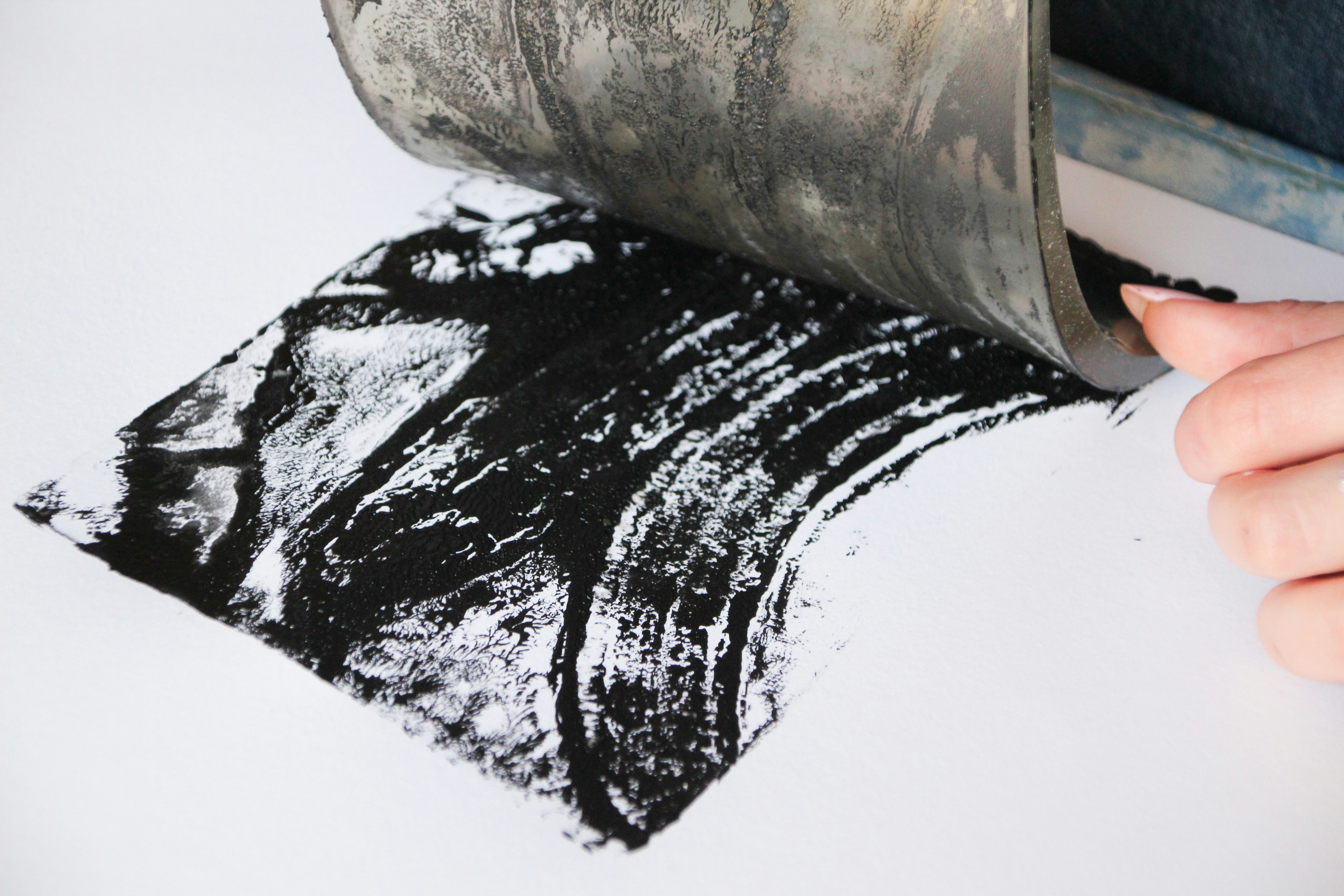 A hand applying black ink to white paper.