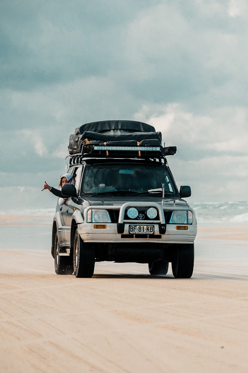 A 4x4 vehicle driving on a sandy beach.