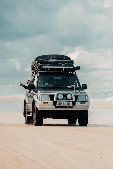A 4x4 vehicle driving on a sandy beach.