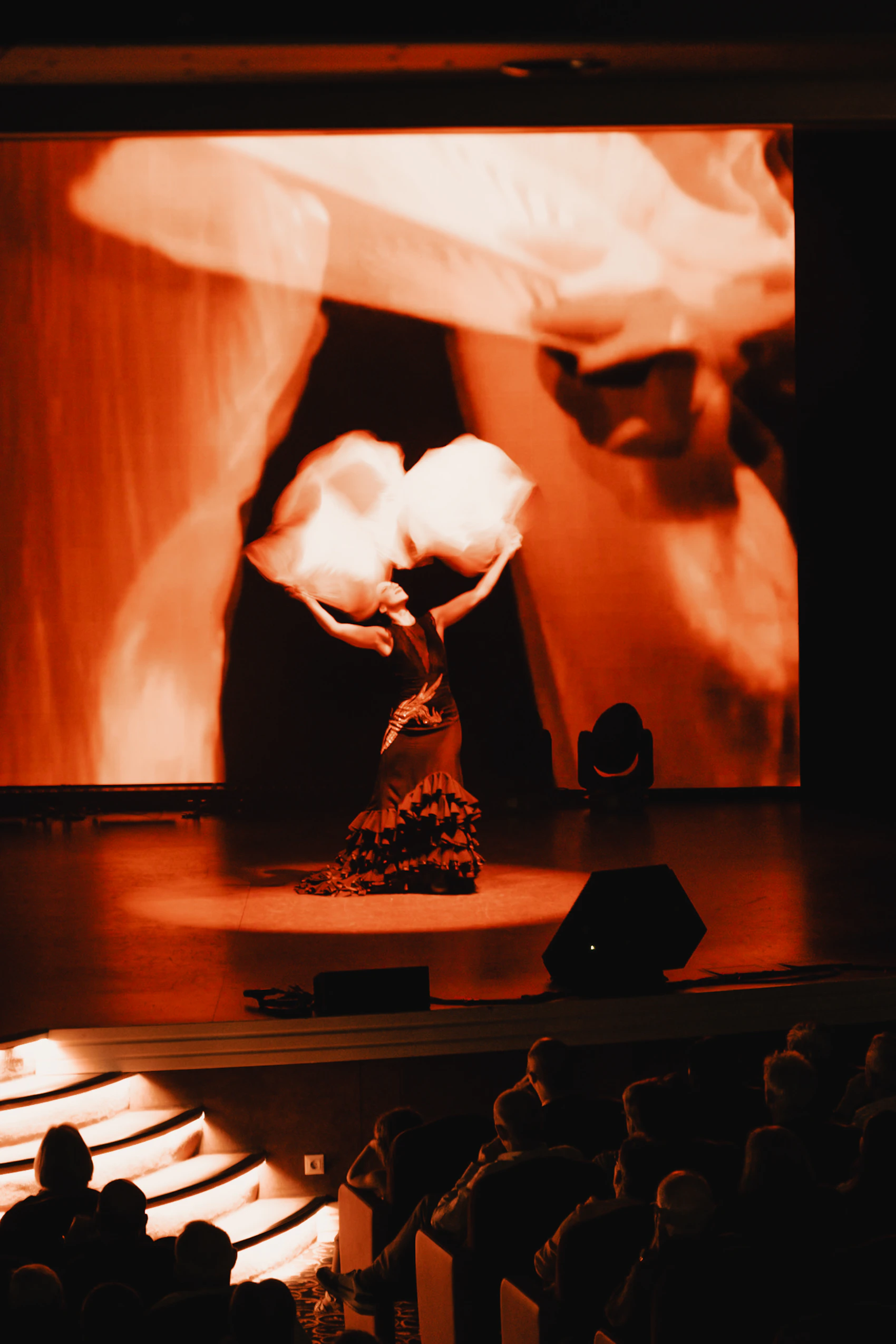 A flamenco dancer performing on stage in Seville against a dramatic red backdrop