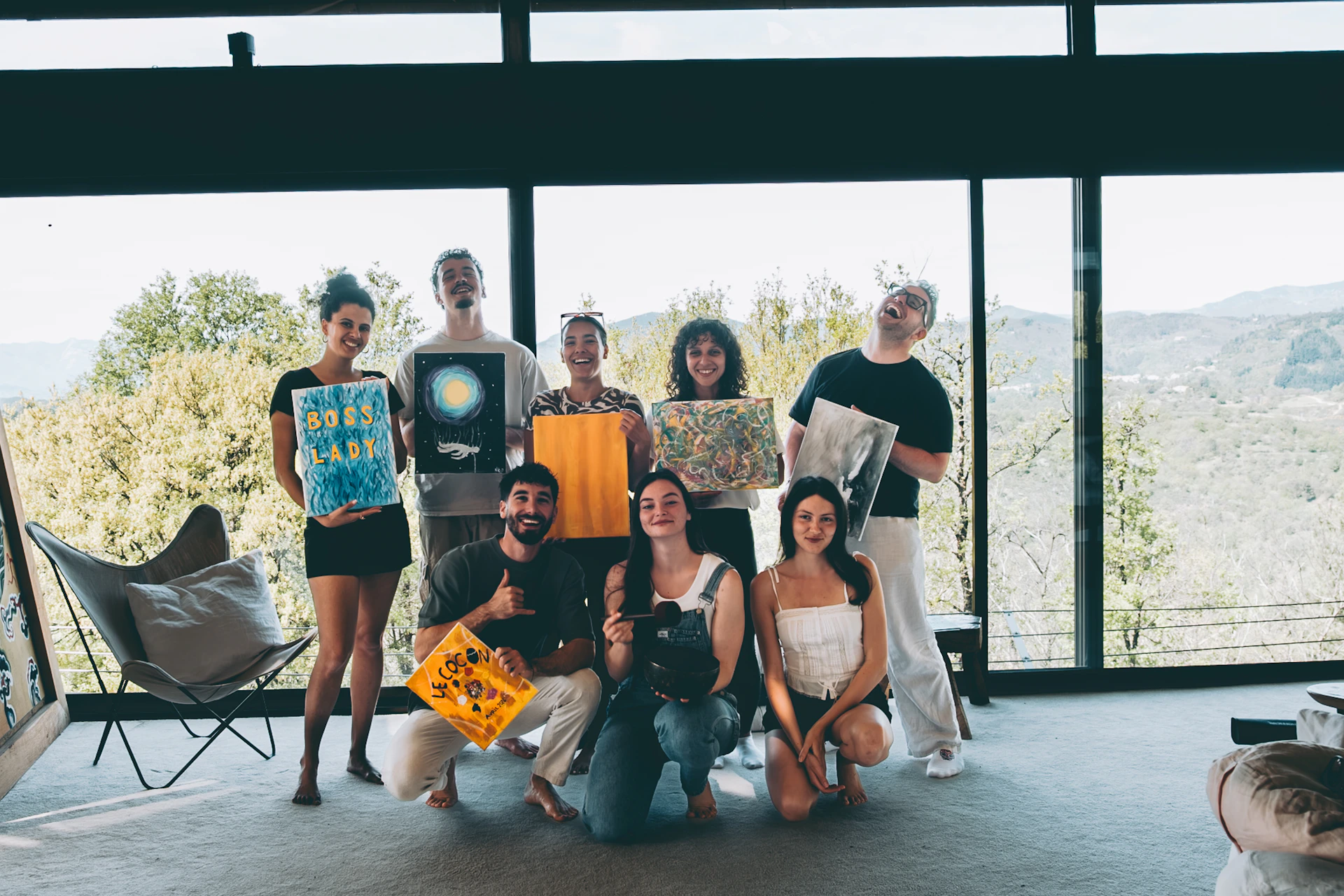 Group of friends holding artwork in a modern home.