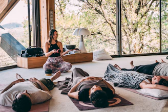Instructor leading a group meditation class in a natural setting.