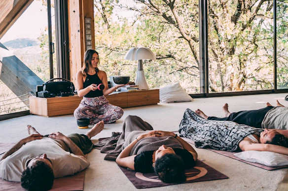 Instructor leading a group meditation class in a natural setting.