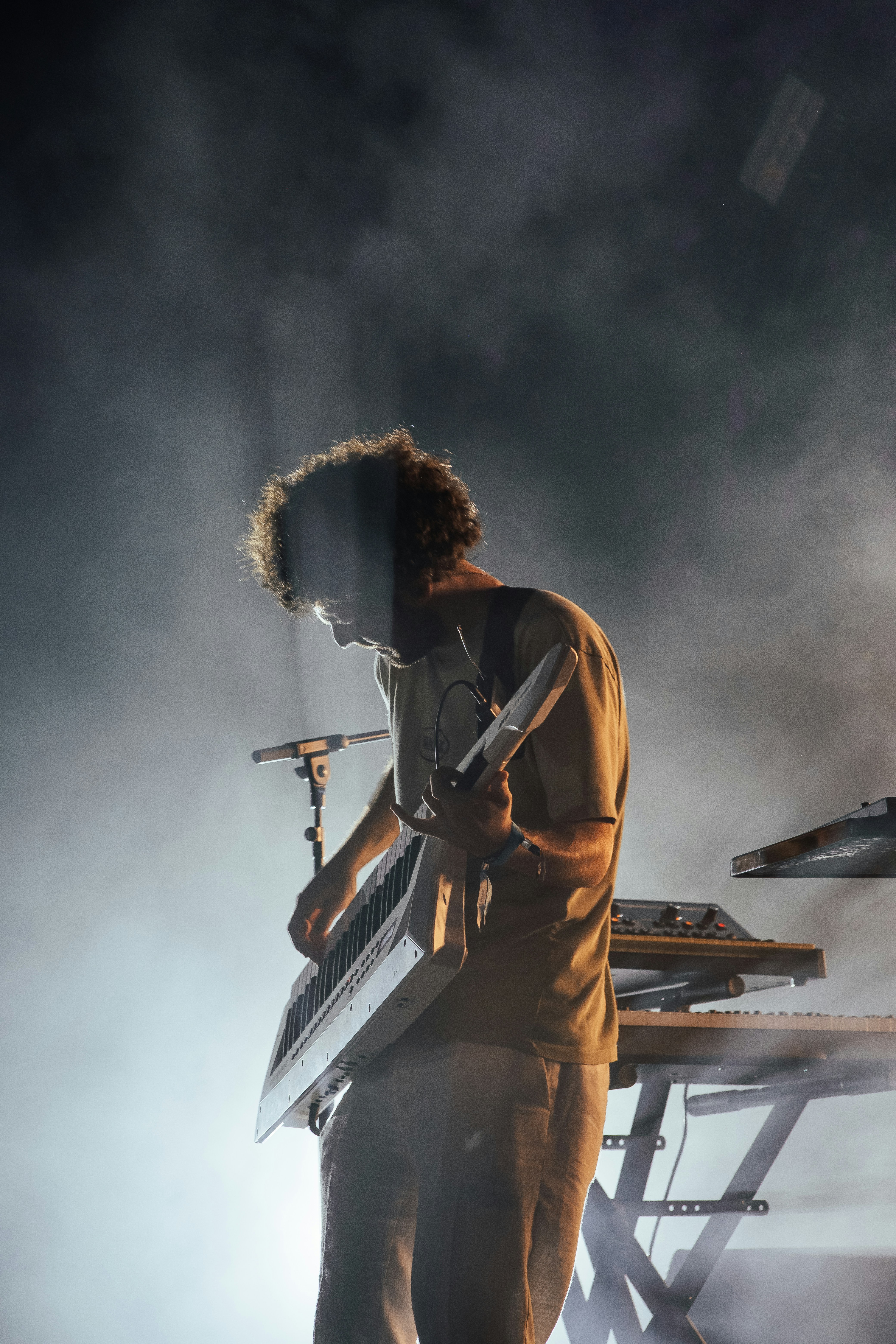 Man playing keyboard synthesizer on stage with smoke