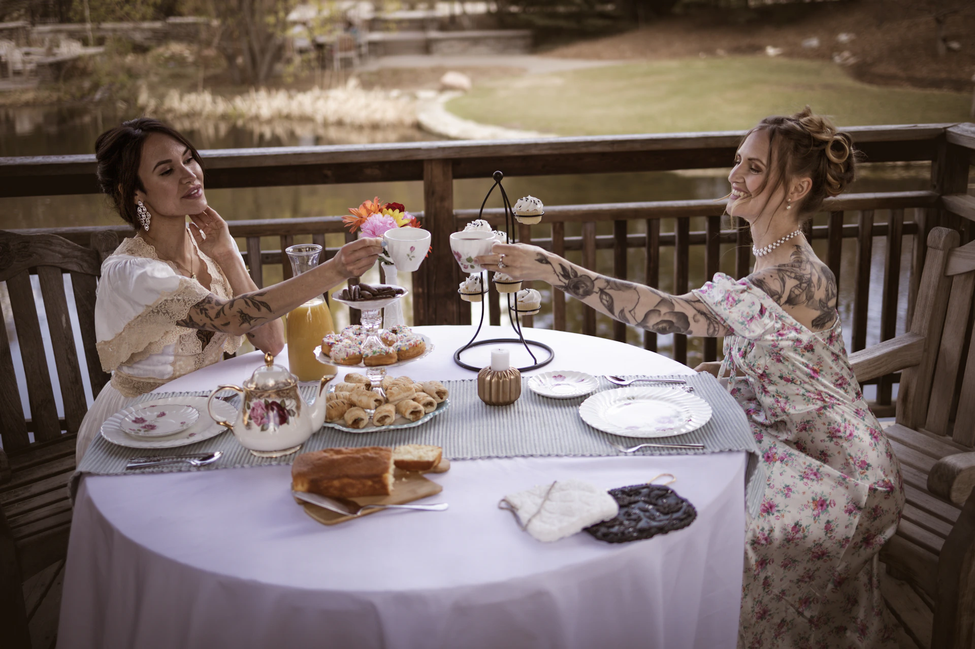 Two women in vintage dresses enjoying tea outdoors