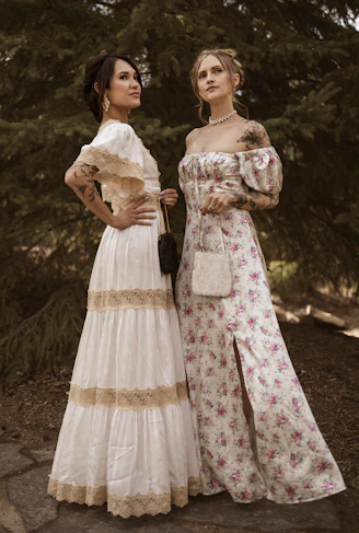 Two women in vintage dresses stand outdoors