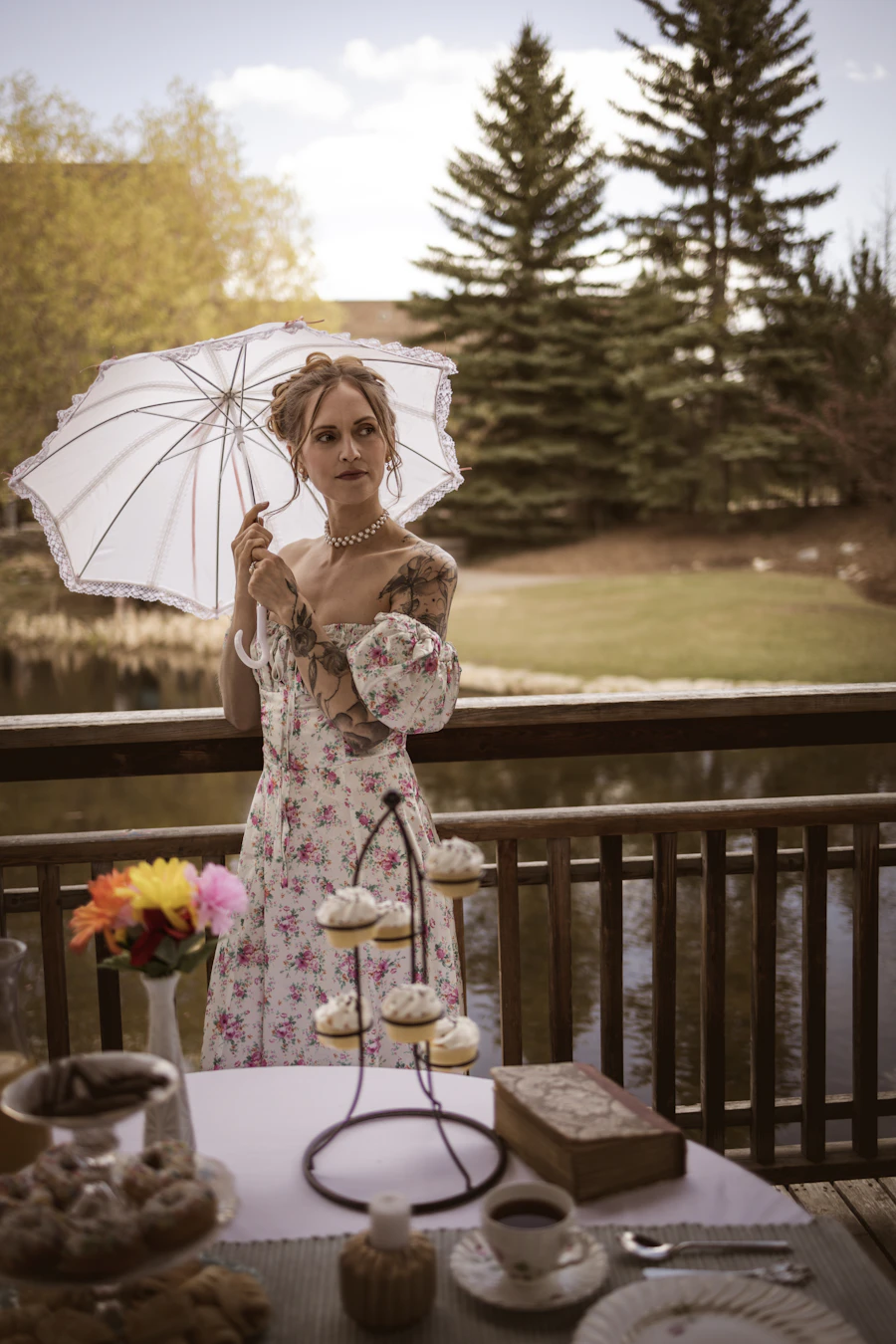 Model with a lace parasol beside a table set for afternoon tea