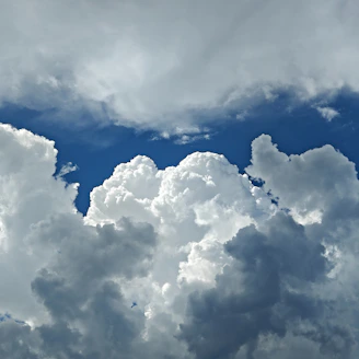 Large white cumulus clouds against a bright blue sky