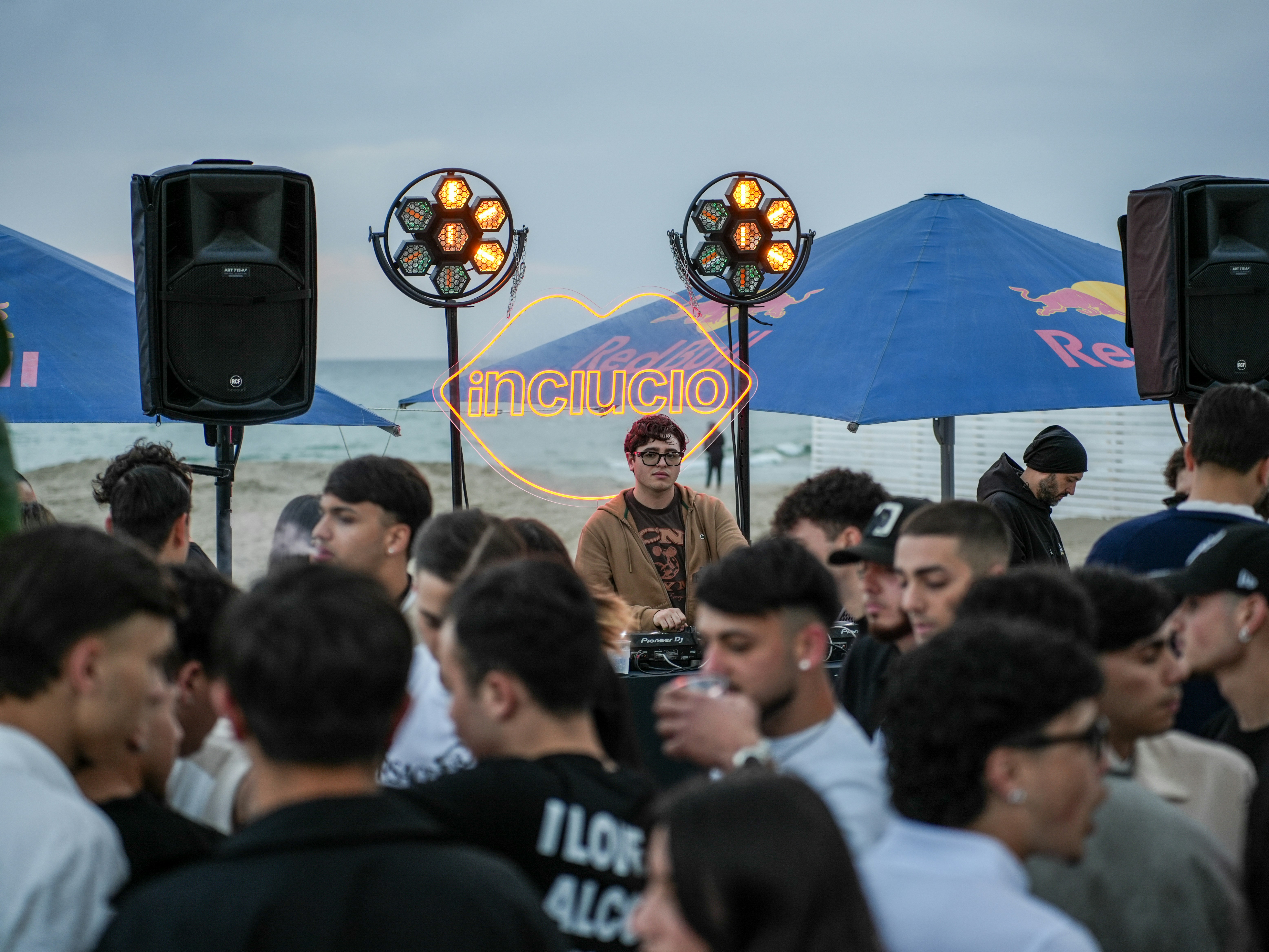 A dj performs for a crowd at a beach party.