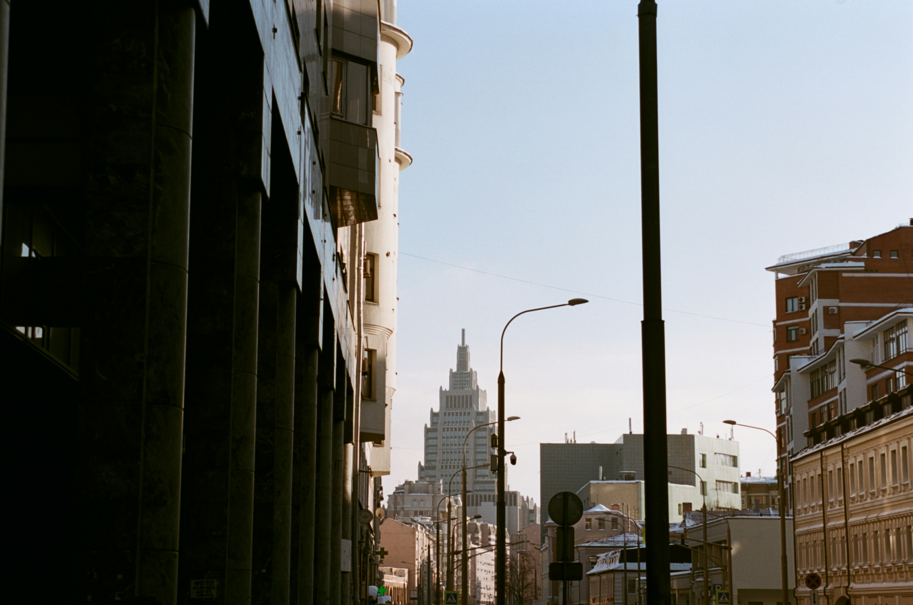 Tall building in a city street with lamp posts.