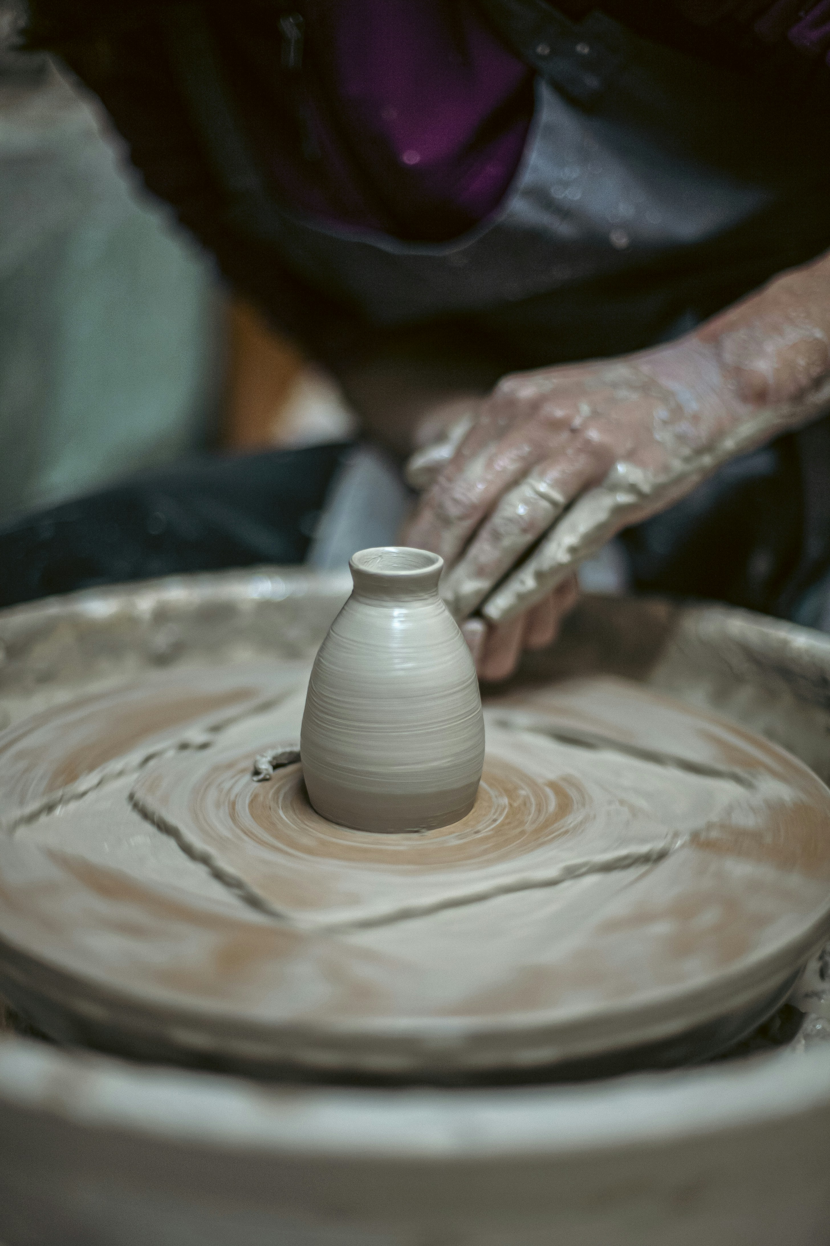 Hands shaping clay on a pottery wheel