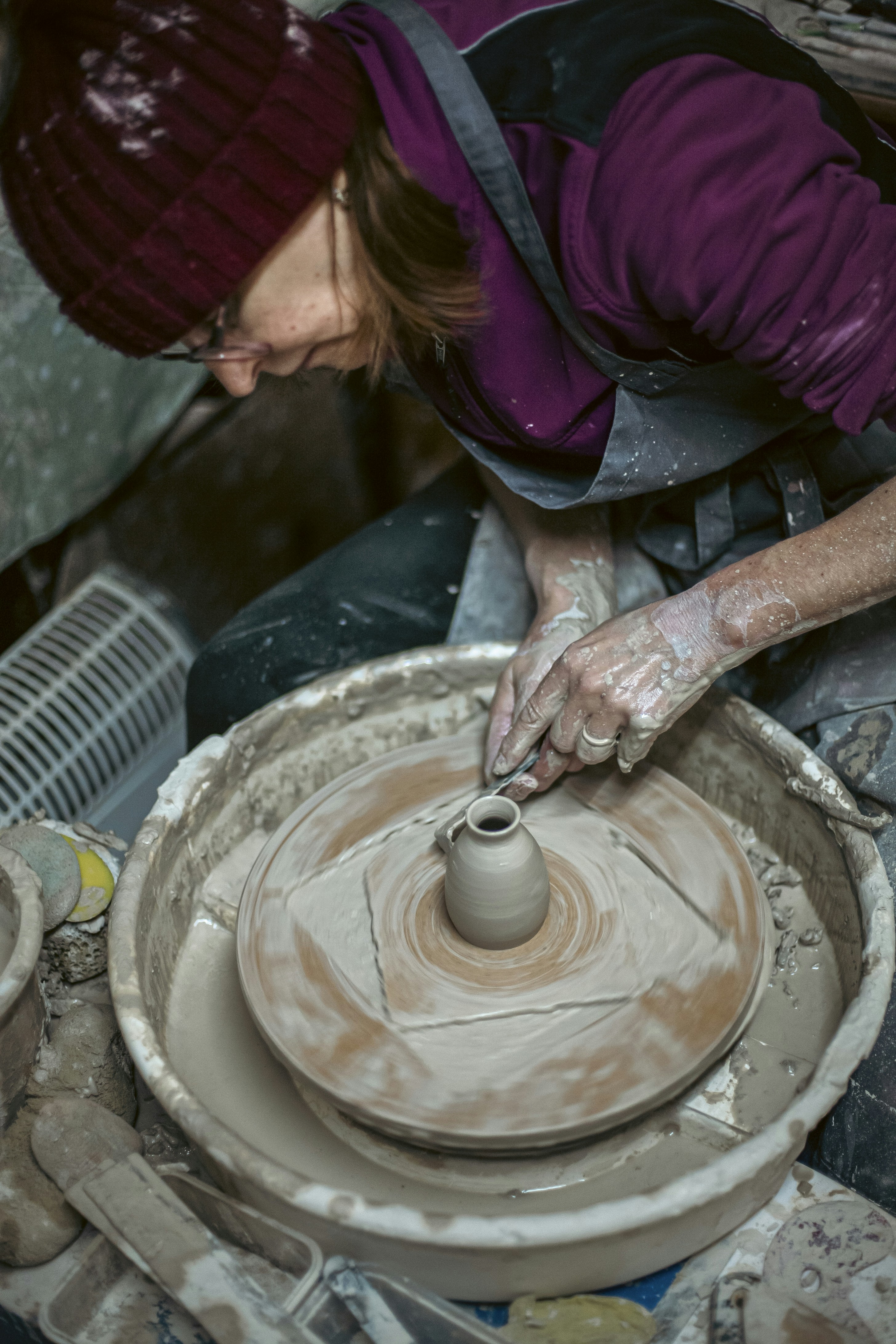 A person shaping clay on a pottery wheel.