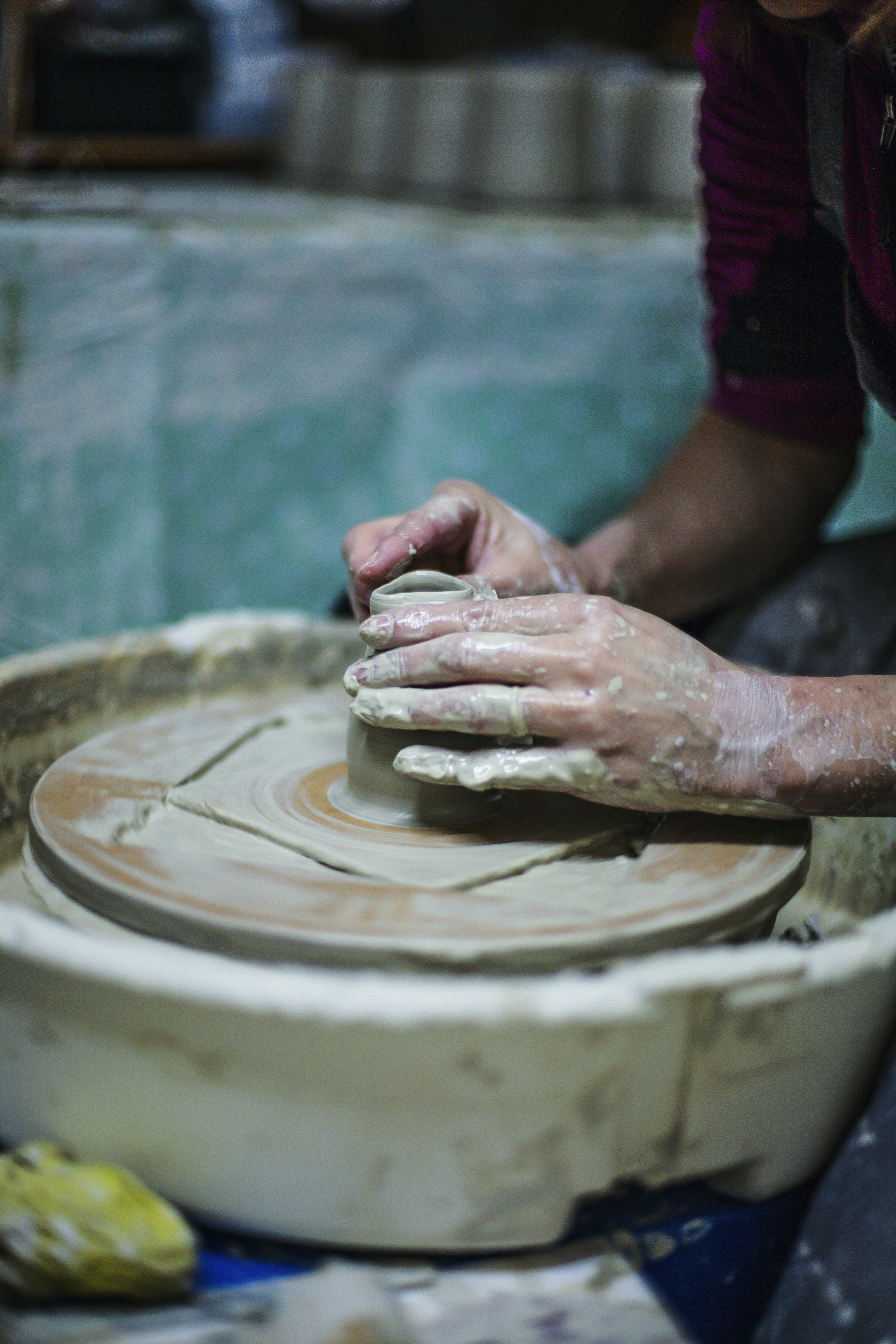 Hands shaping clay on a pottery wheel