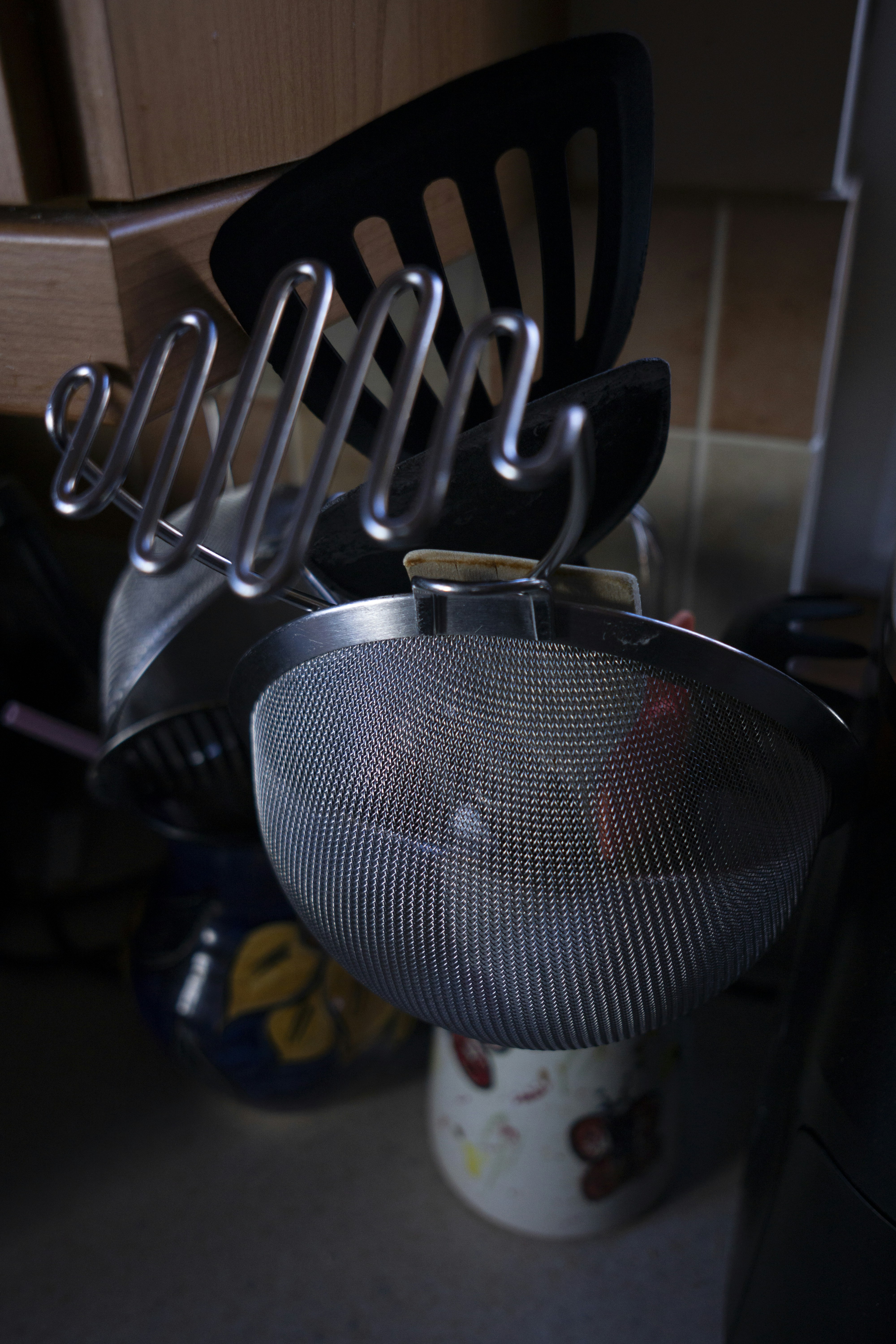 Metal strainer, slotted spatula, and potato masher in a kitchen.