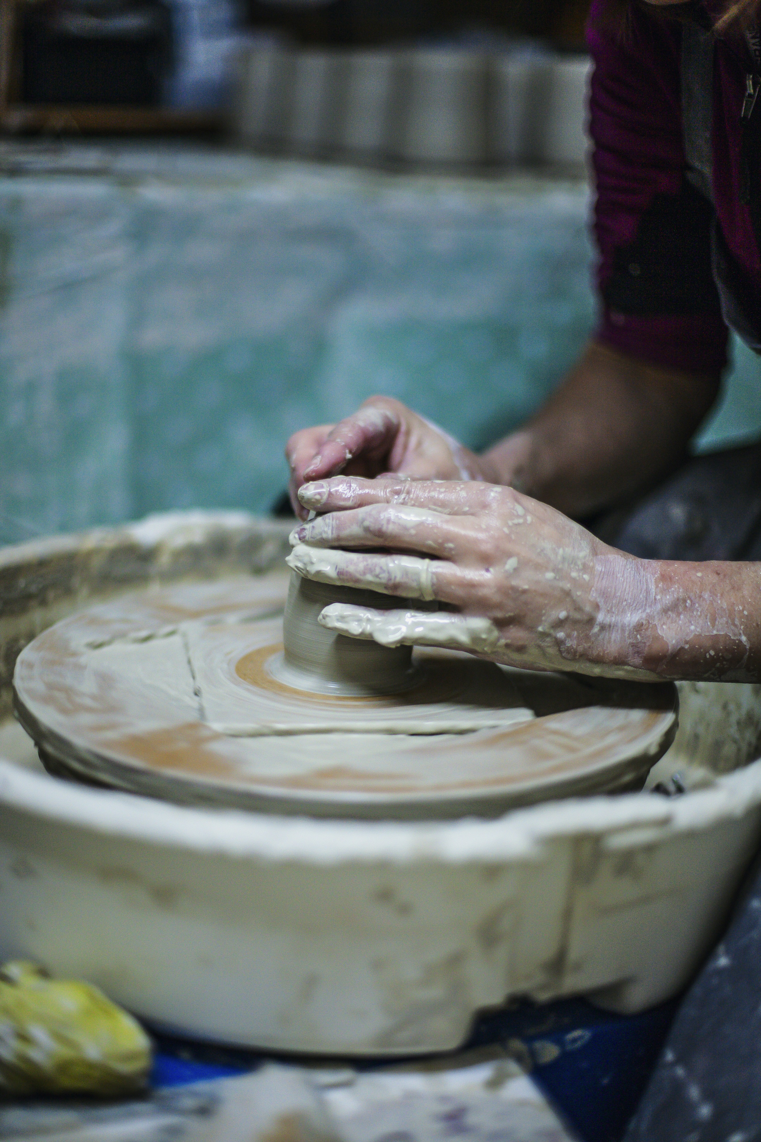 Hands shaping clay on a pottery wheel