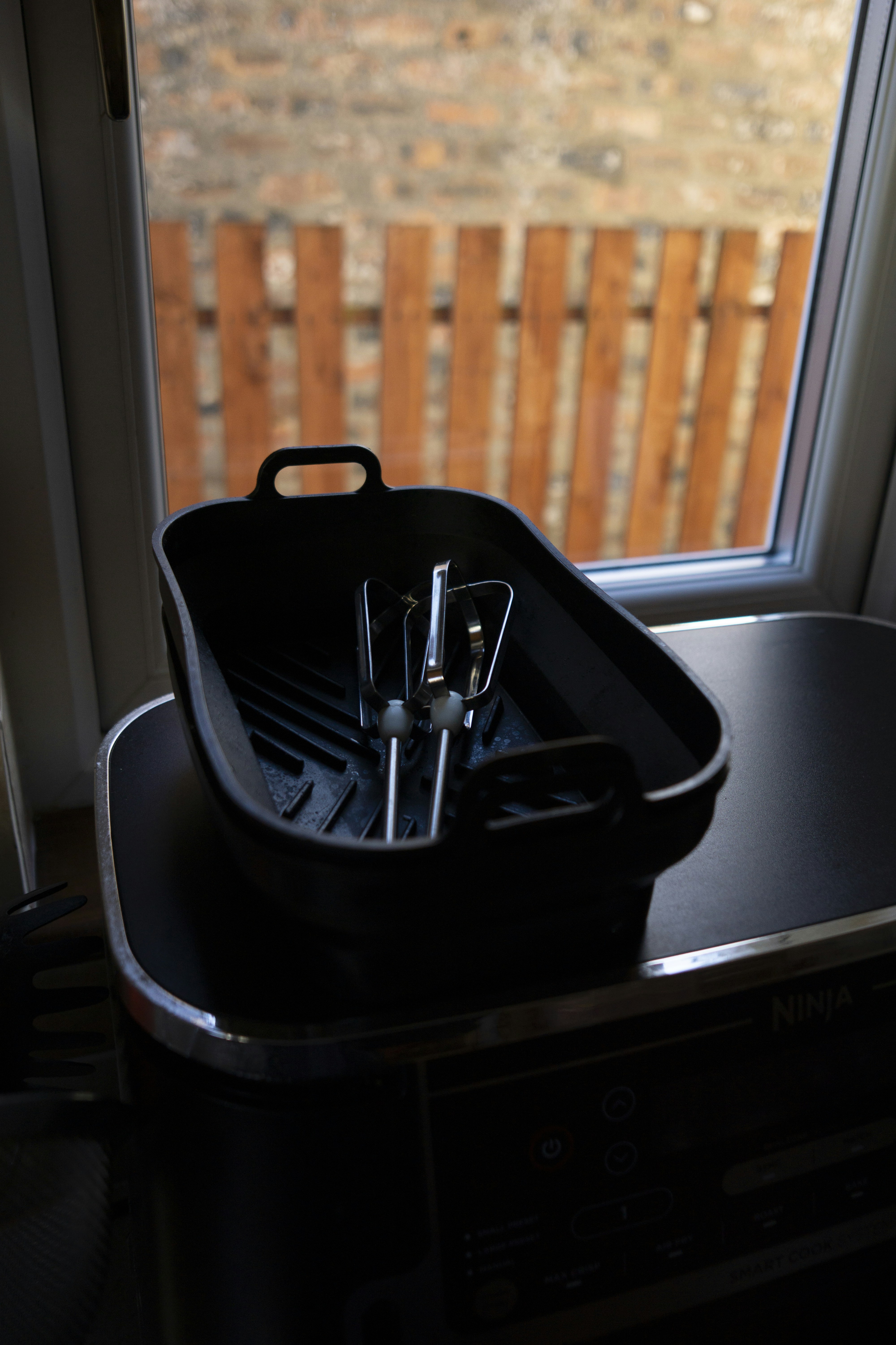 A black roasting pan with utensils on a table.