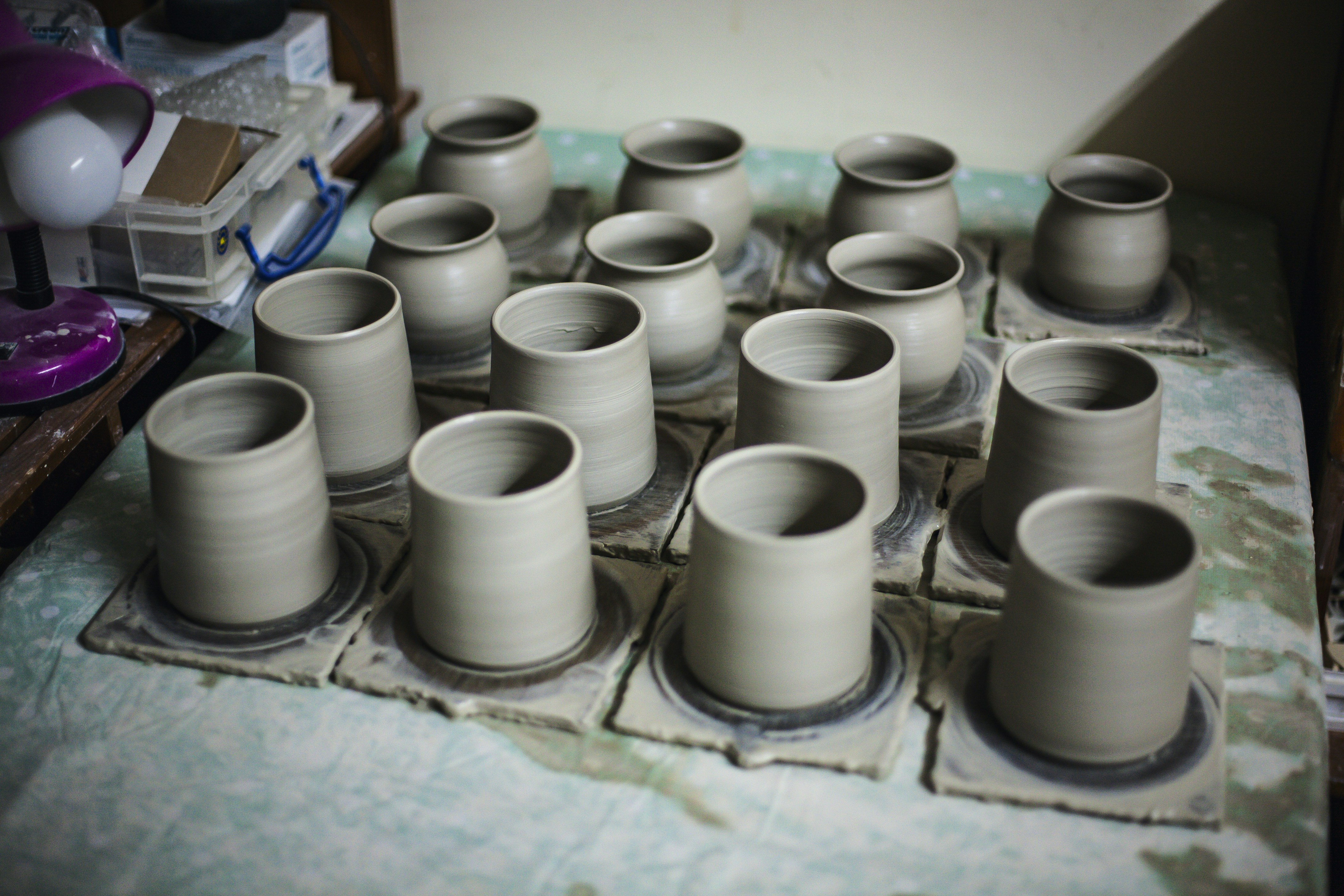 Many unfinished ceramic pots drying on a surface.