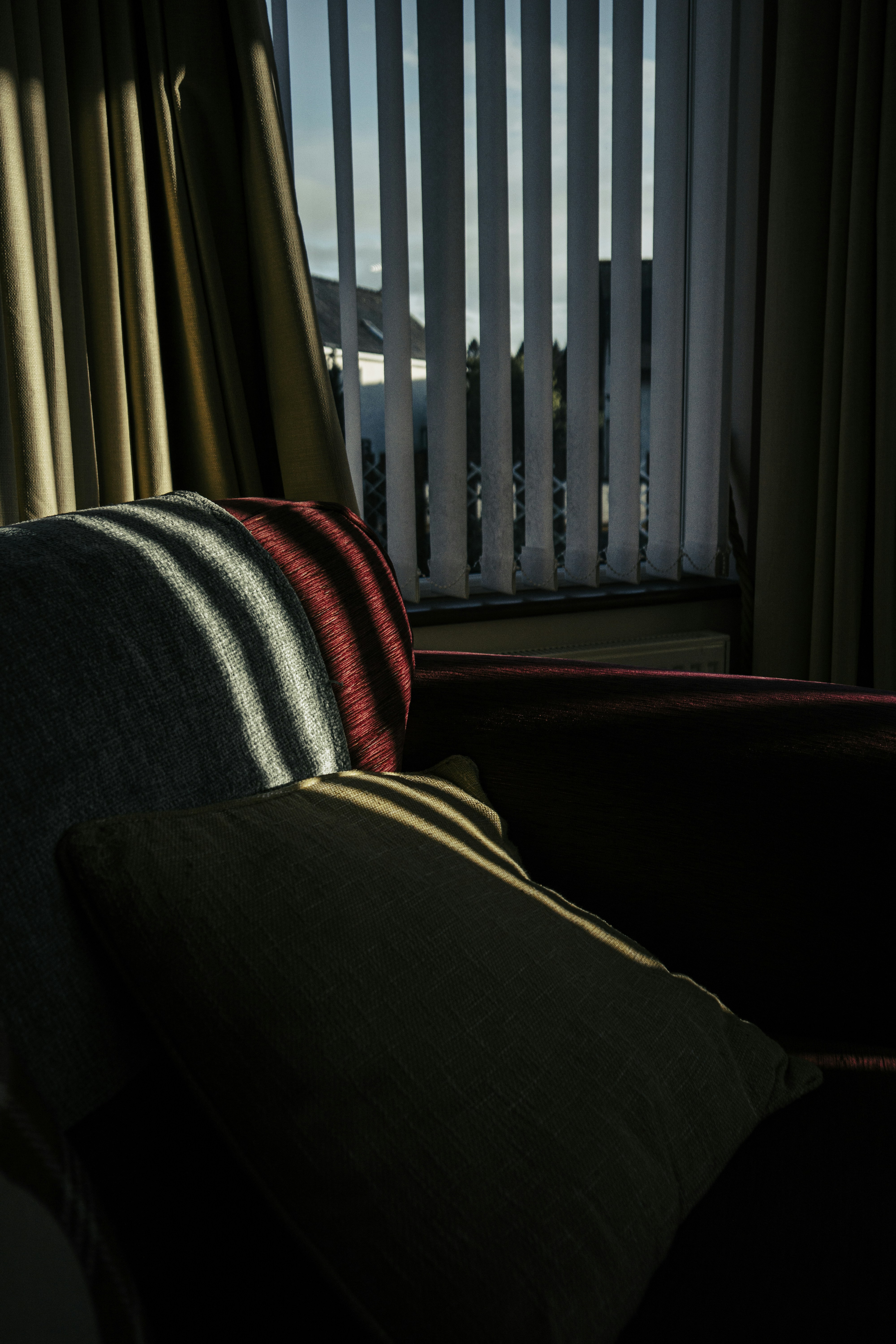 Sunlight streams through blinds onto a couch.