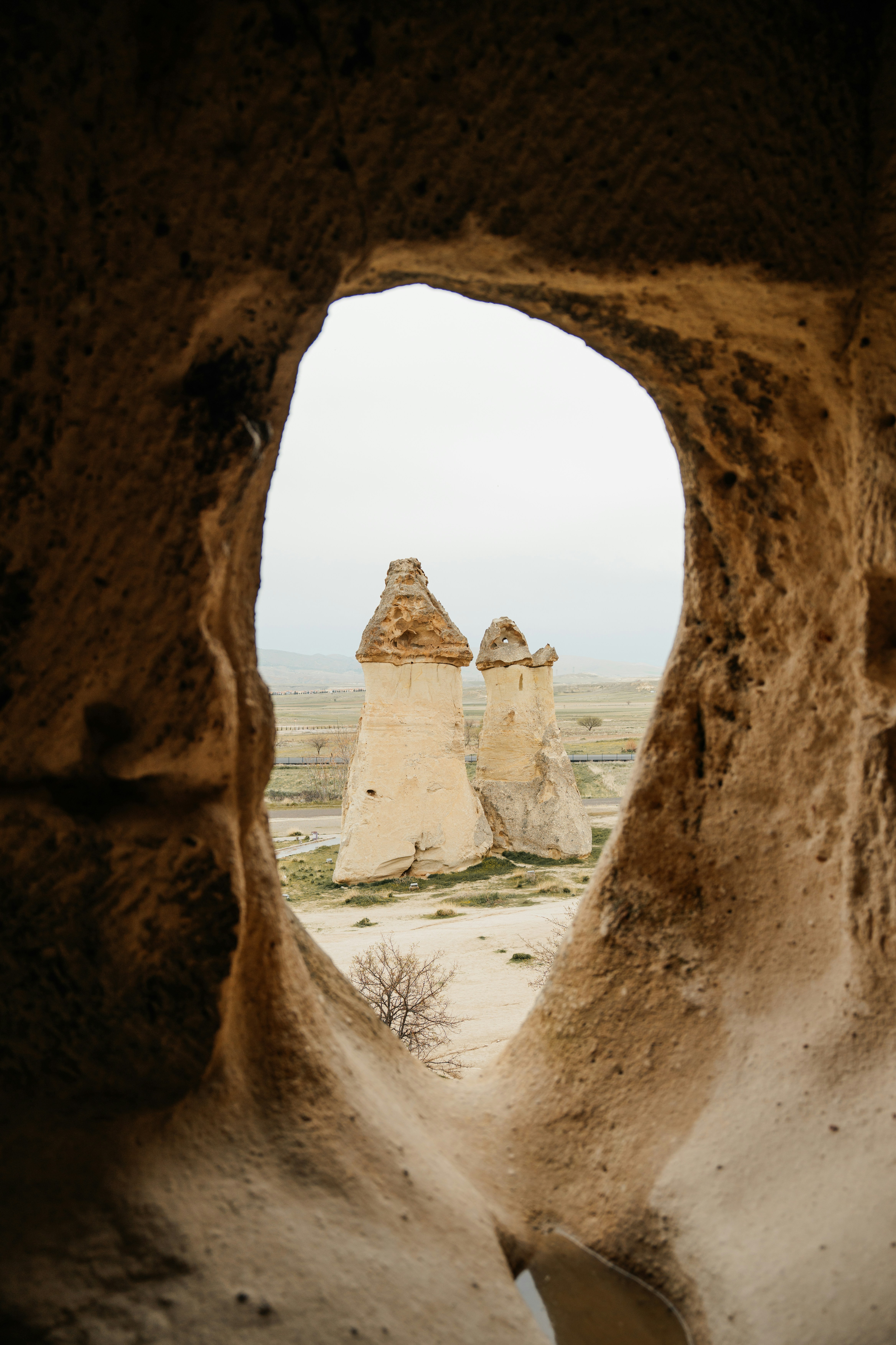 Fairy chimney rock formations viewed through a cave opening.