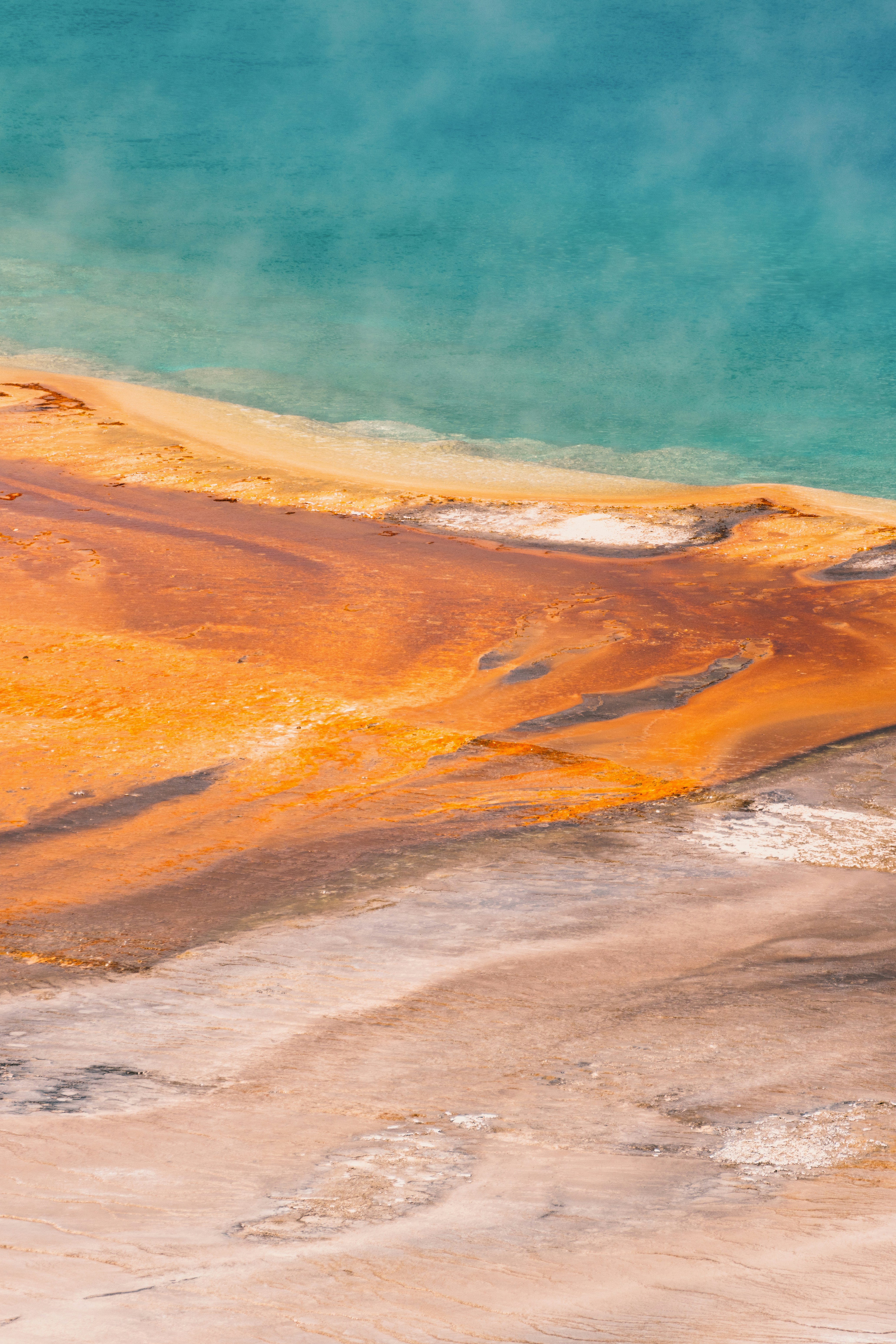 Colorful geothermal spring with turquoise water and orange mineral terraces.