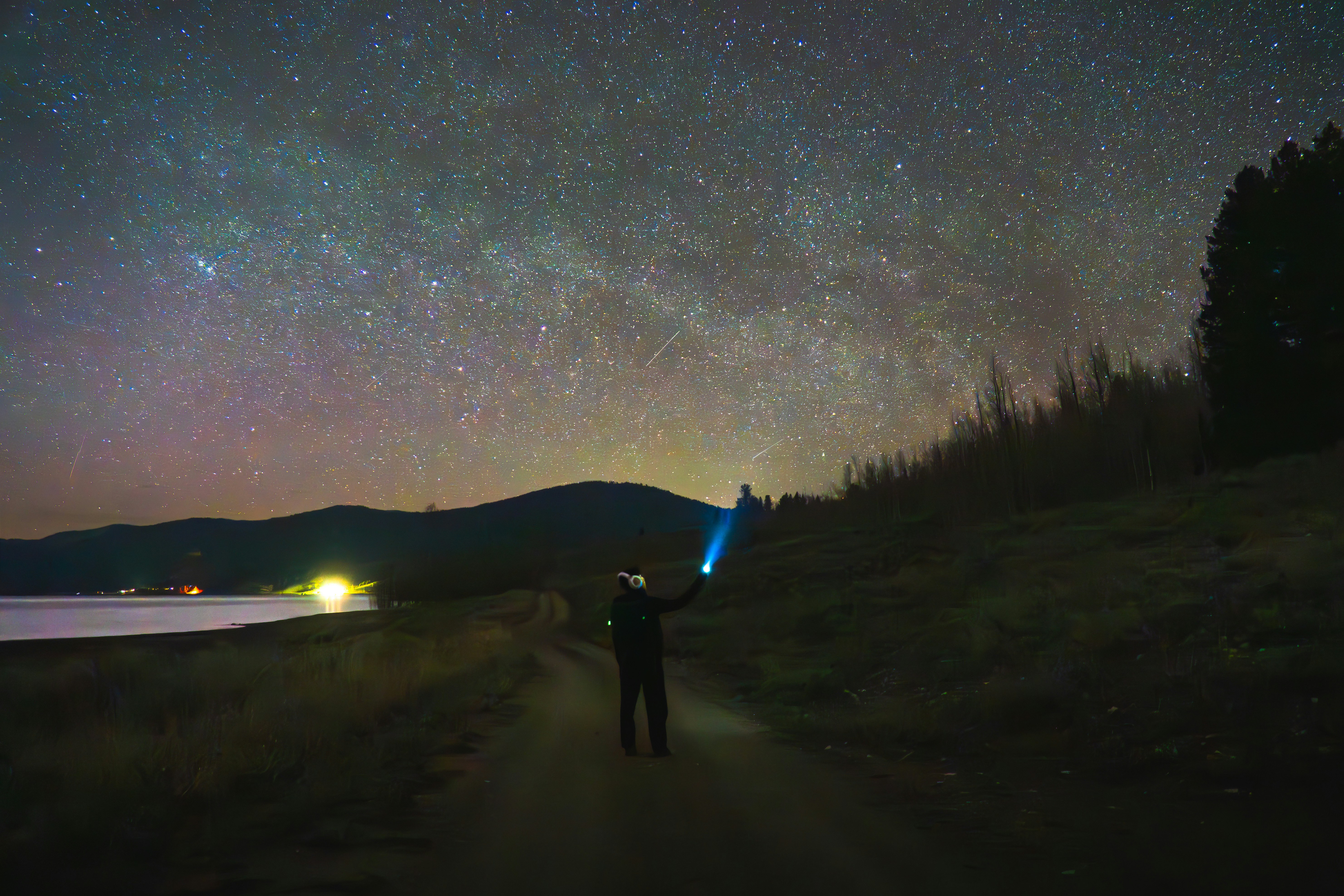 Photo of Person with flashlight under a vibrant starry night sky. by Samuel Quek