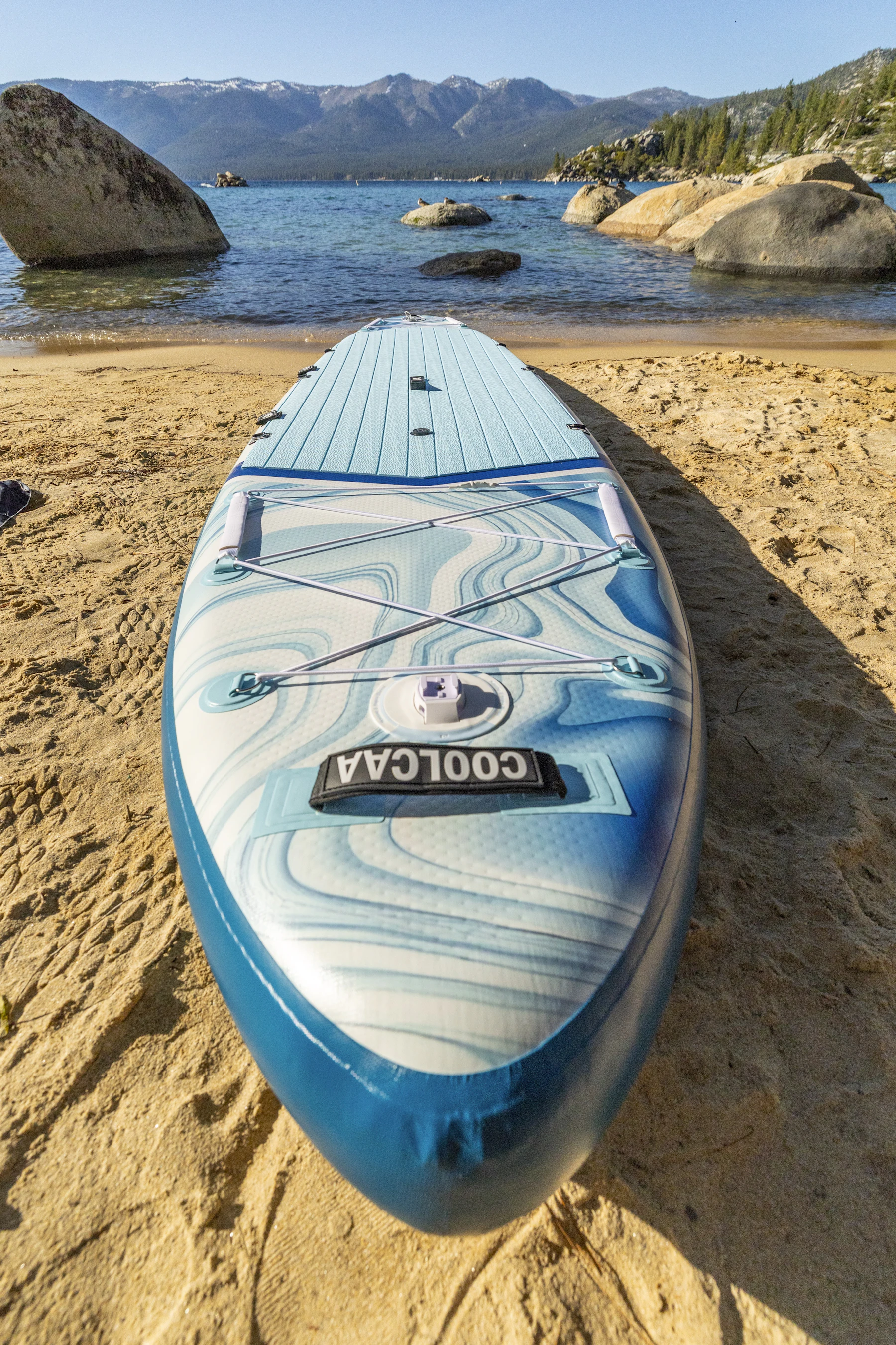 Stand-up paddleboard resting on a sandy lakeside beach