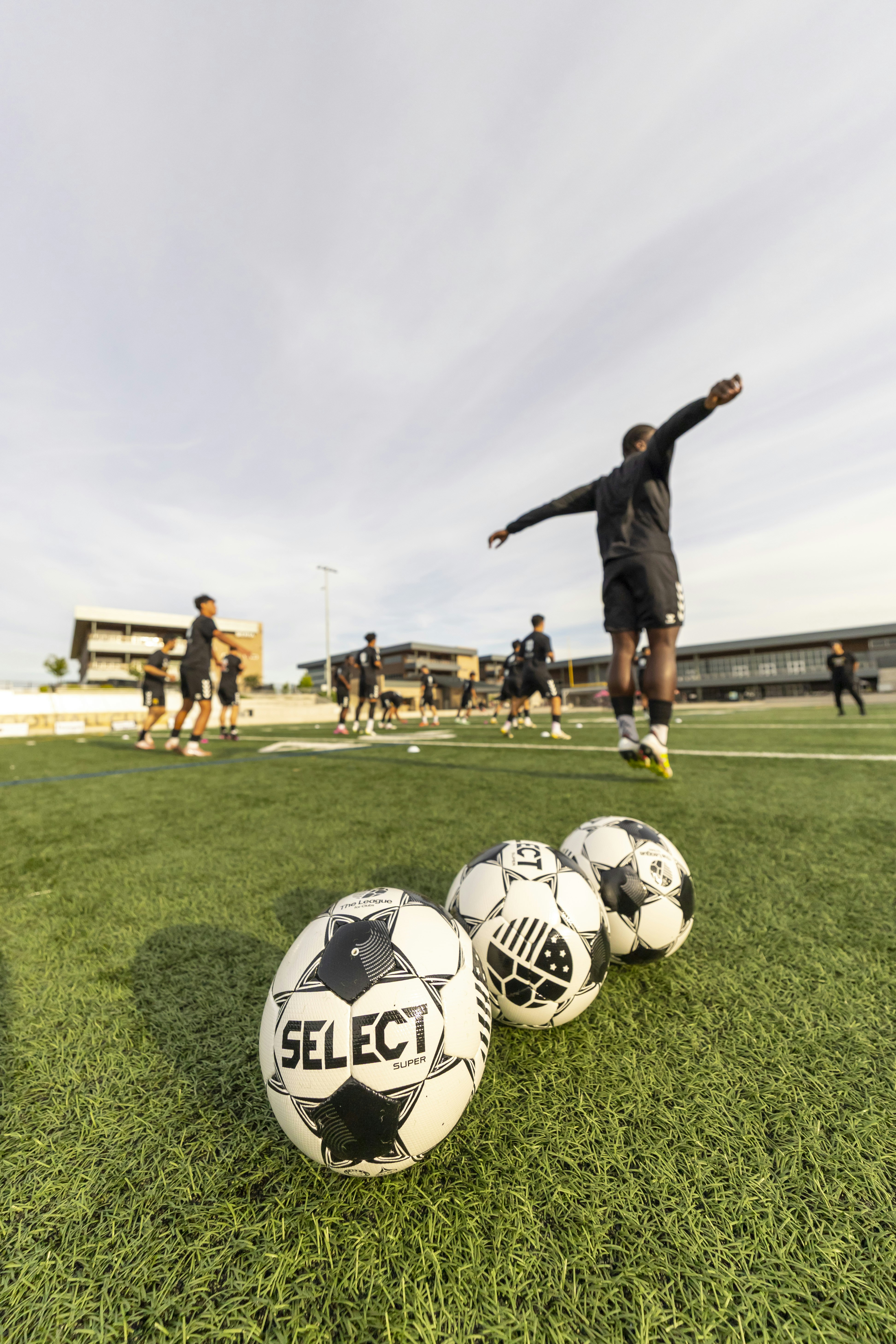 選手たちがトレーニングしている中、フィールドにはサッカーボールが並んでいました
