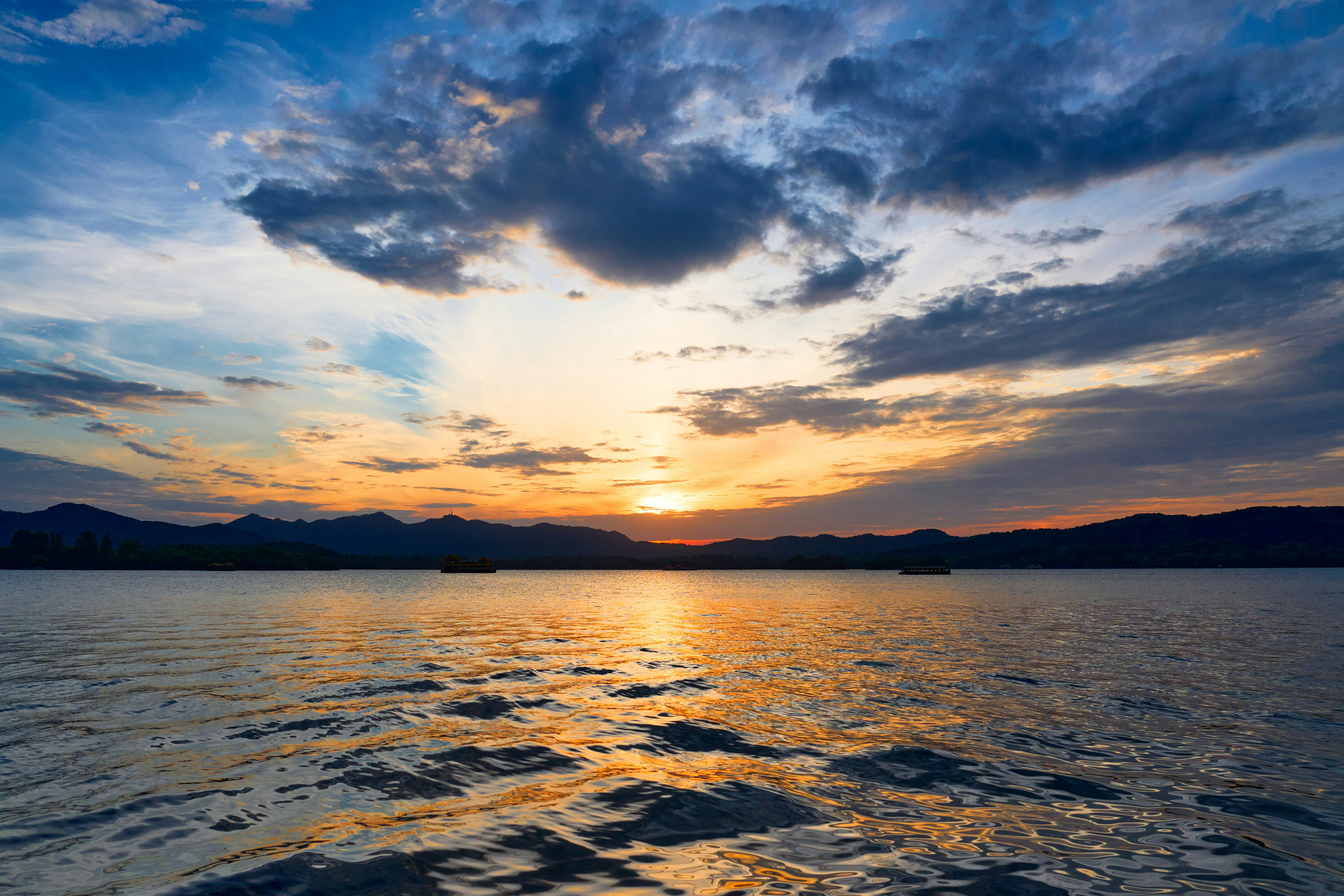 Pôr do sol sobre um lago calmo com montanhas ao longe