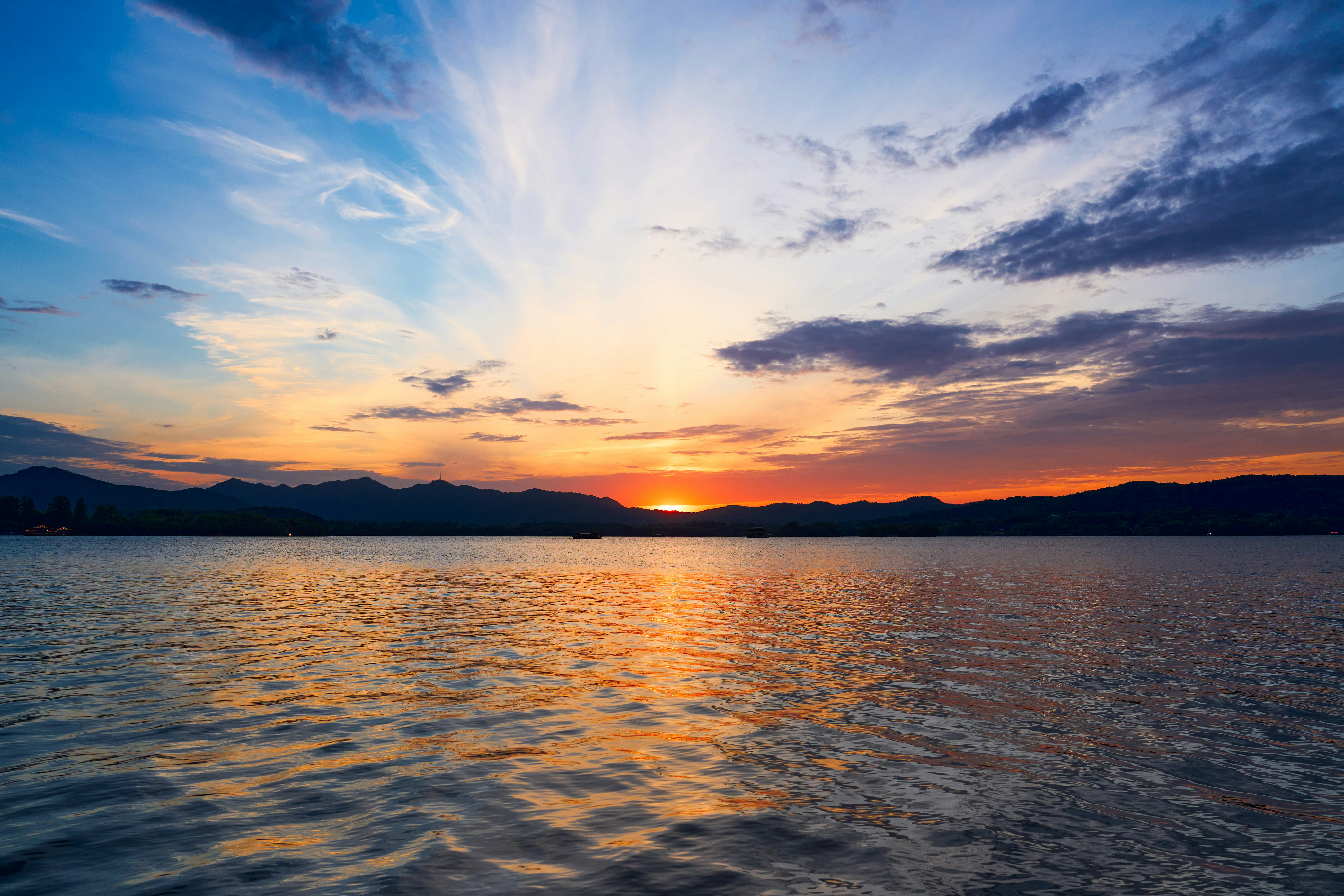 Um pôr do sol vibrante sobre um lago calmo com montanhas distantes.