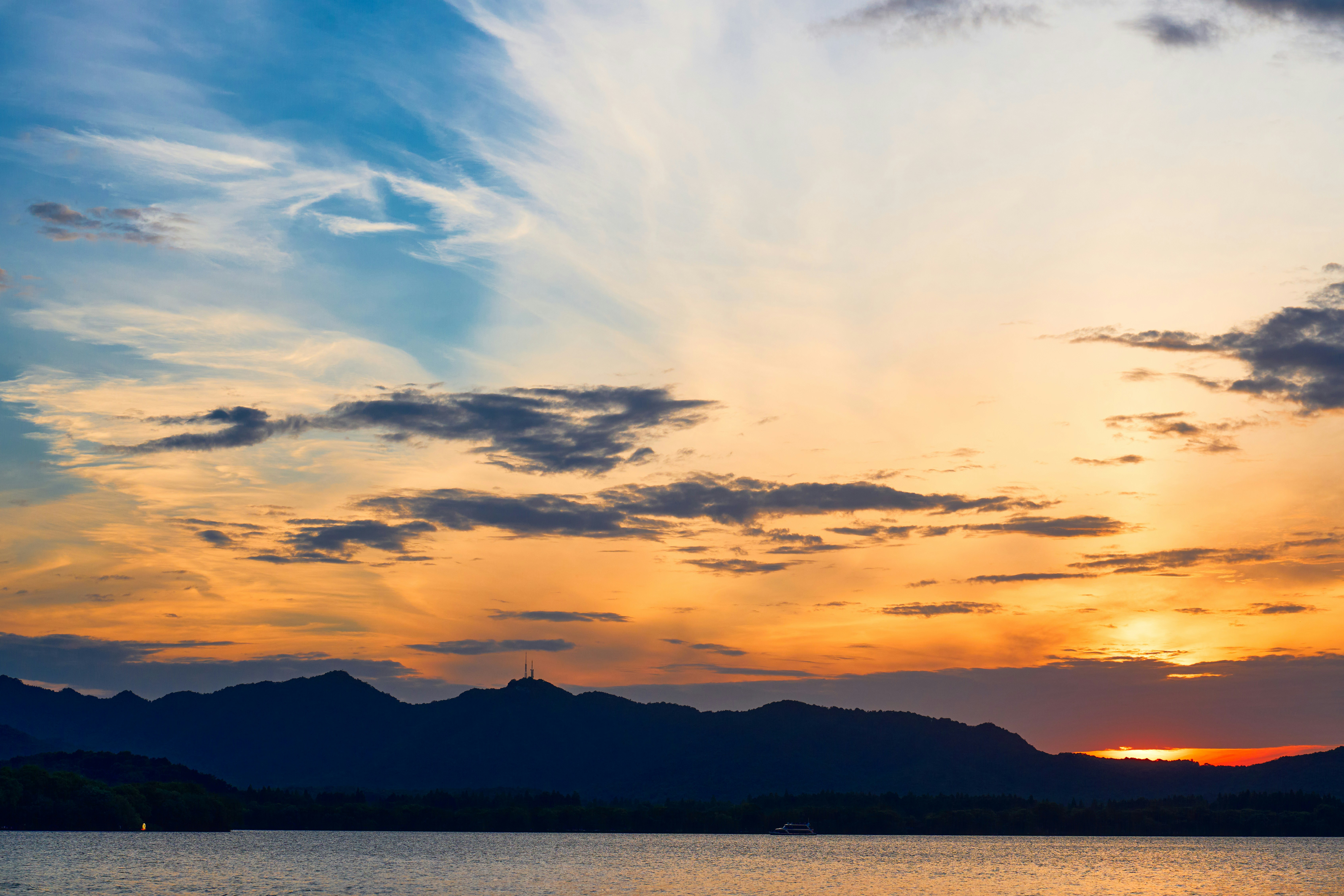 Pôr do sol sobre um lago calmo com montanhas