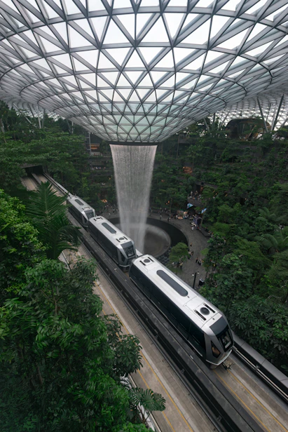 Modern train passes waterfall in lush indoor garden