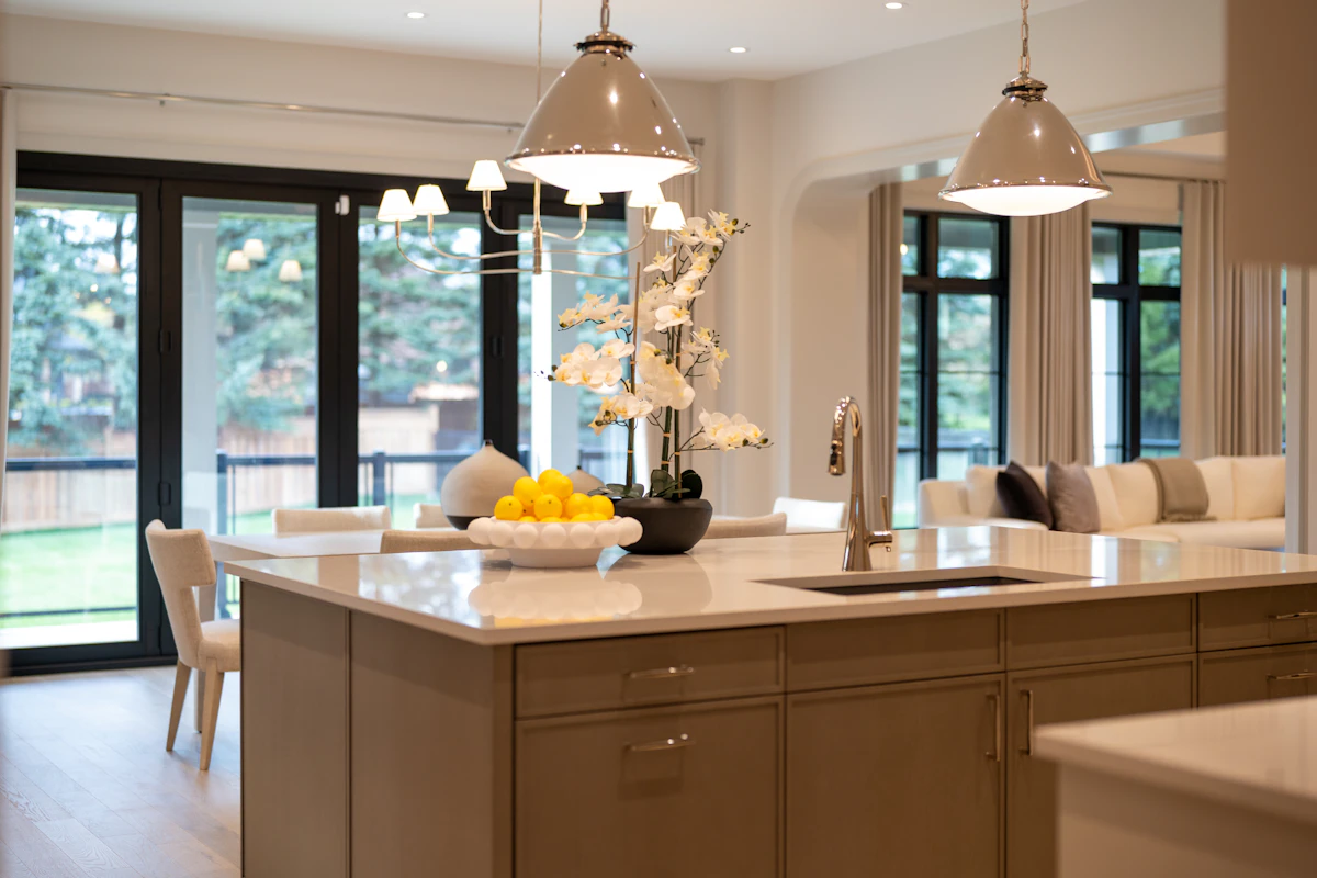 A warm wood island with brass pendants and garden doors