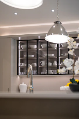 Modern kitchen with illuminated glass cabinets displaying dishes.
