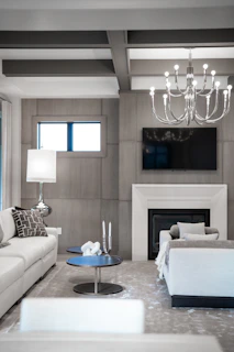 Modern living room with white sofas, fireplace, and chandelier