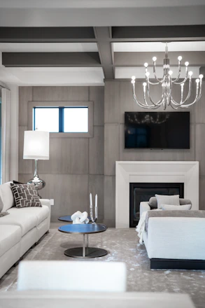 Modern living room with white sofas, fireplace, and chandelier