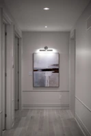 A modern hallway with an abstract painting and recessed lighting.