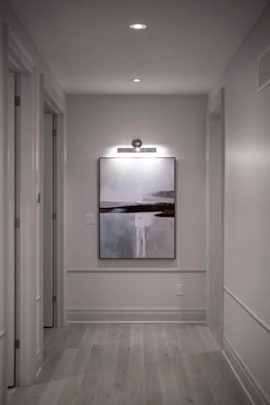 A modern hallway with an abstract painting and recessed lighting.
