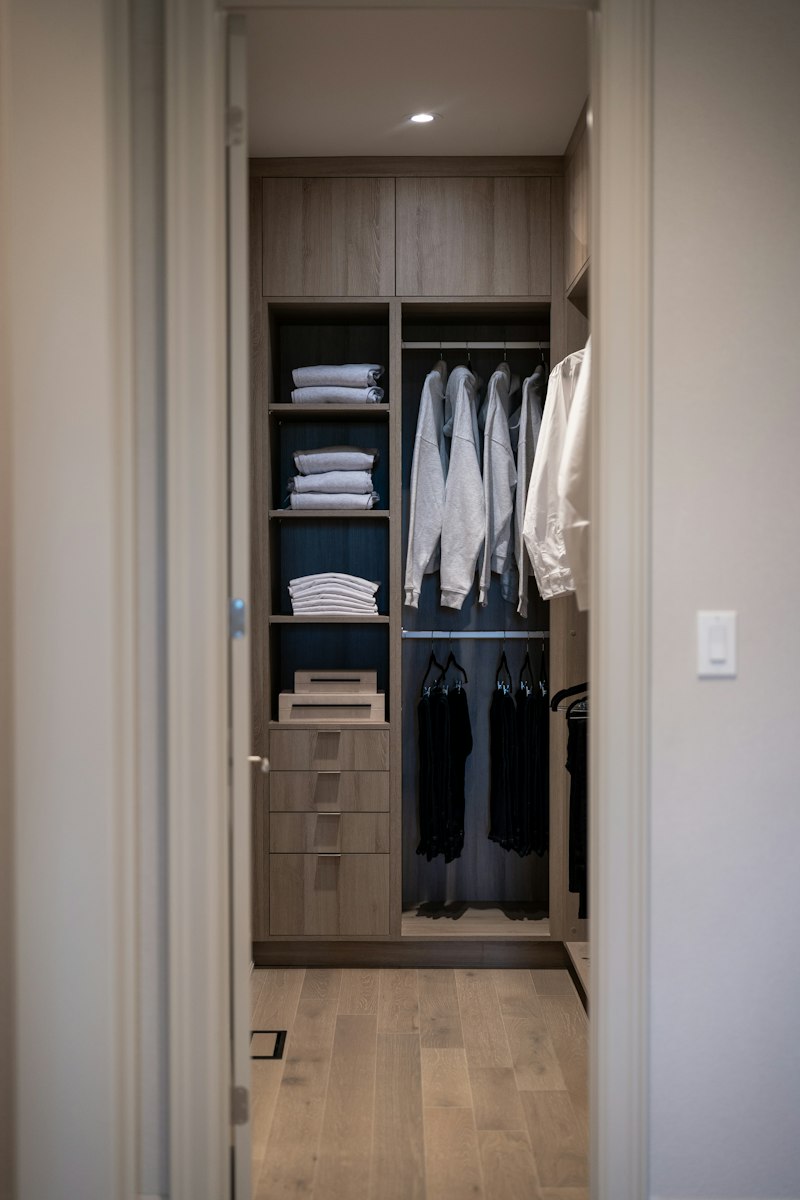 Modern walk-in closet with organized clothing, shelves and drawers