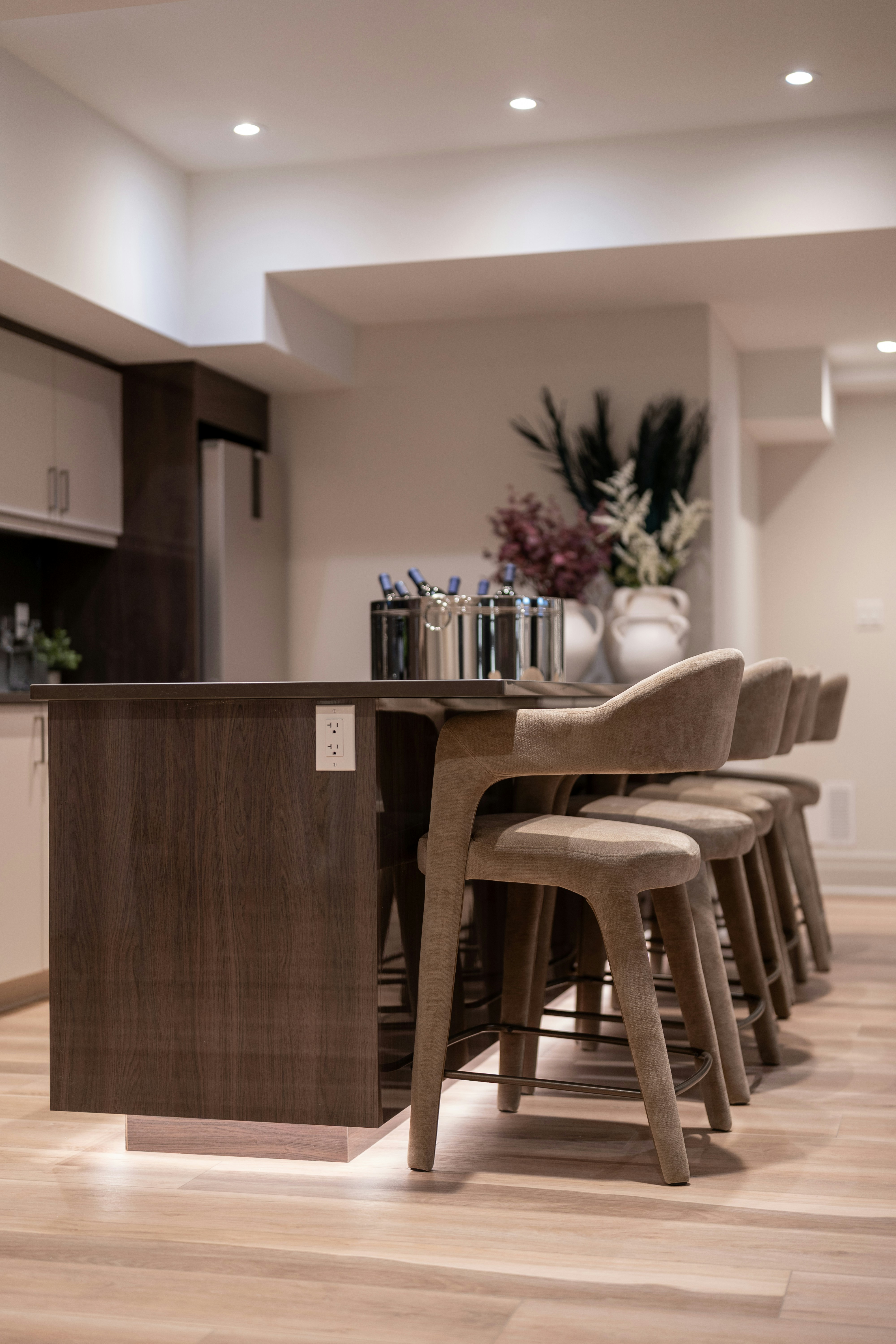 Modern kitchen island with bar stools and decorative vases.