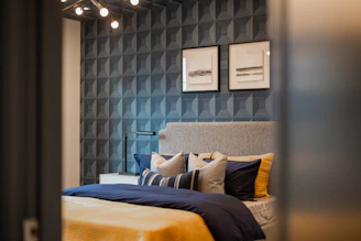 A modern bedroom with a textured blue wall and artwork.