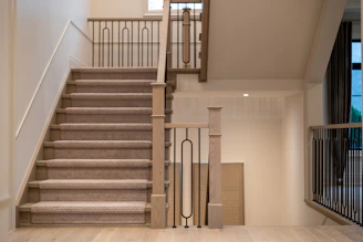 A modern staircase with carpeted steps and elegant metal railings