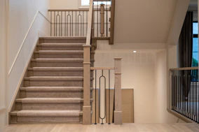 A modern staircase with carpeted steps and elegant metal railings