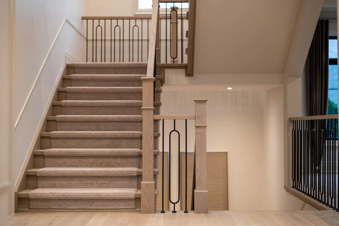 Residential staircase with elegant black metal railings and wood newel posts