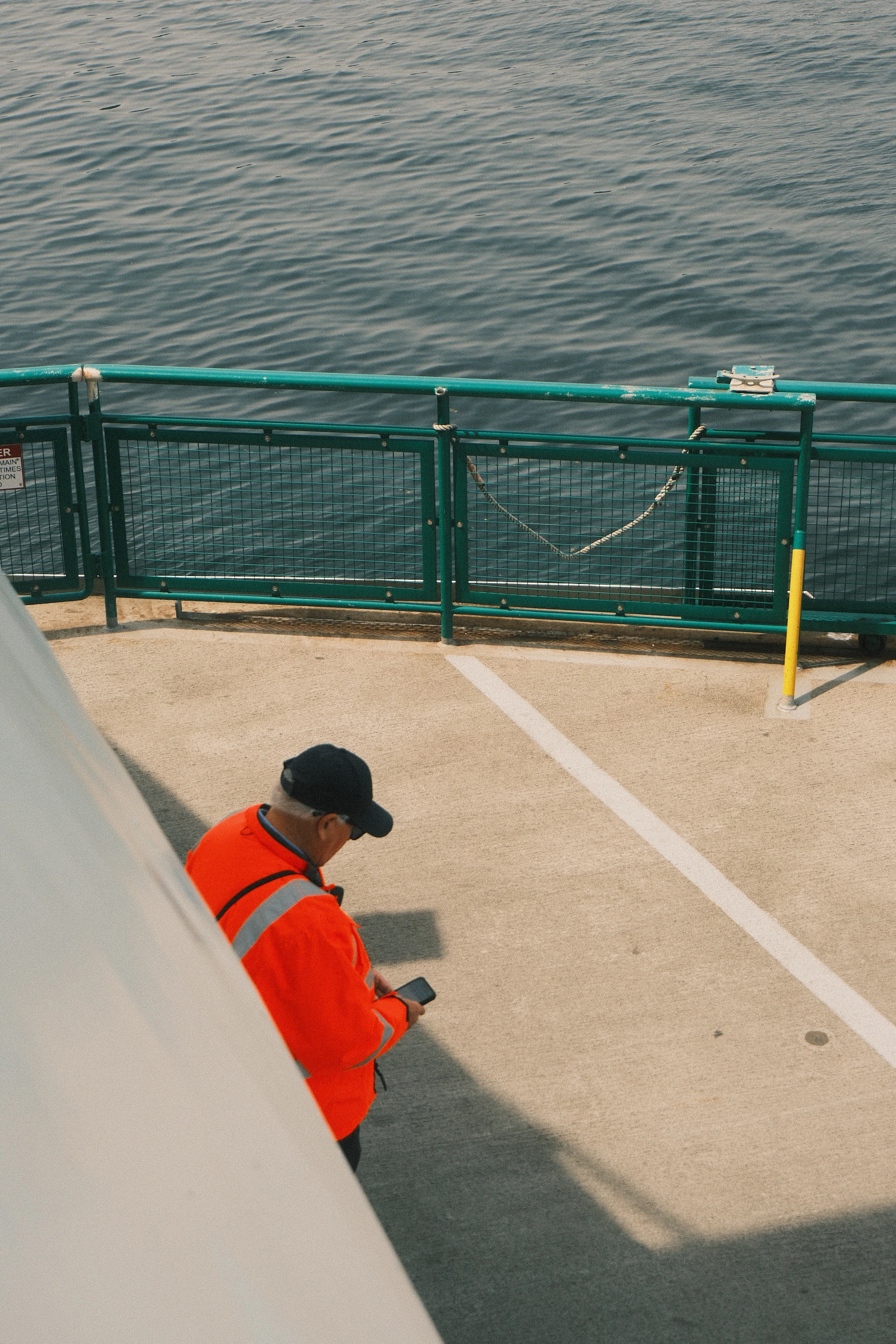 Man in orange jacket using phone on ferry deck