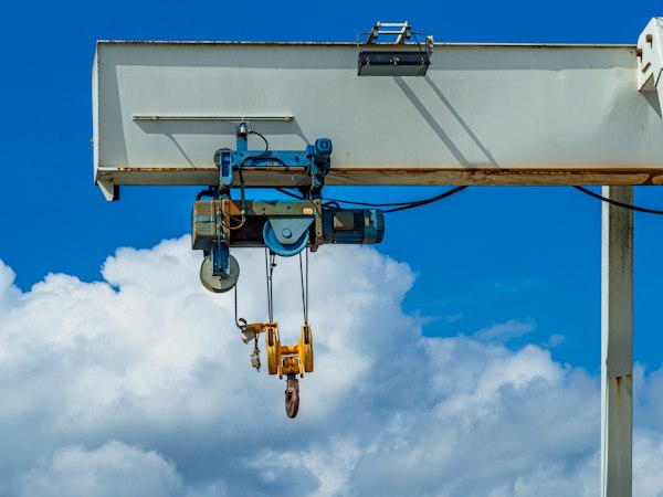 Grúa pórtico industrial con ganchos de izaje recortada contra el cielo, contexto del marketing para empresas de maquinaria industrial