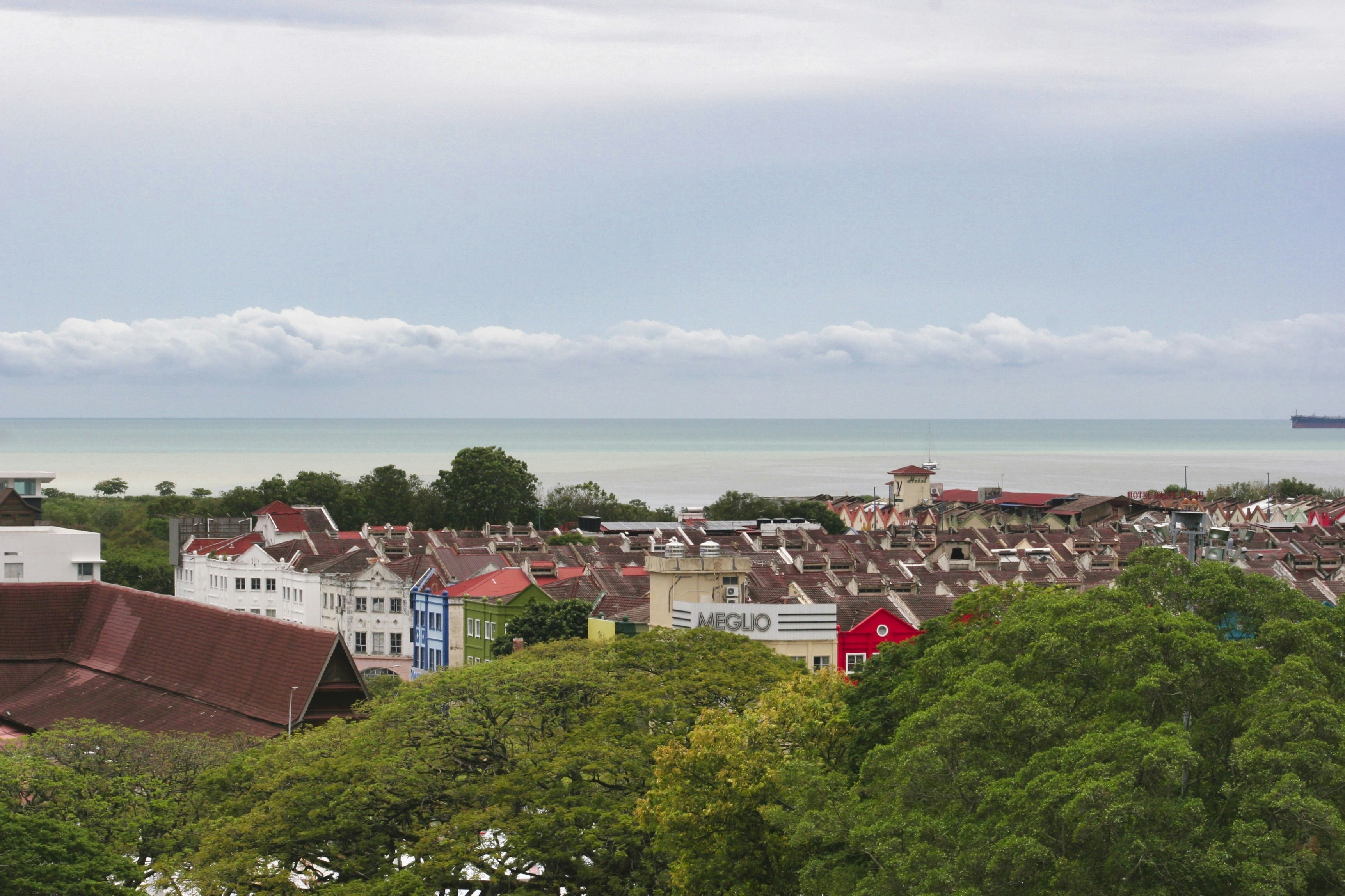 Colorful town rooftops overlooking the ocean under a cloudy sky.