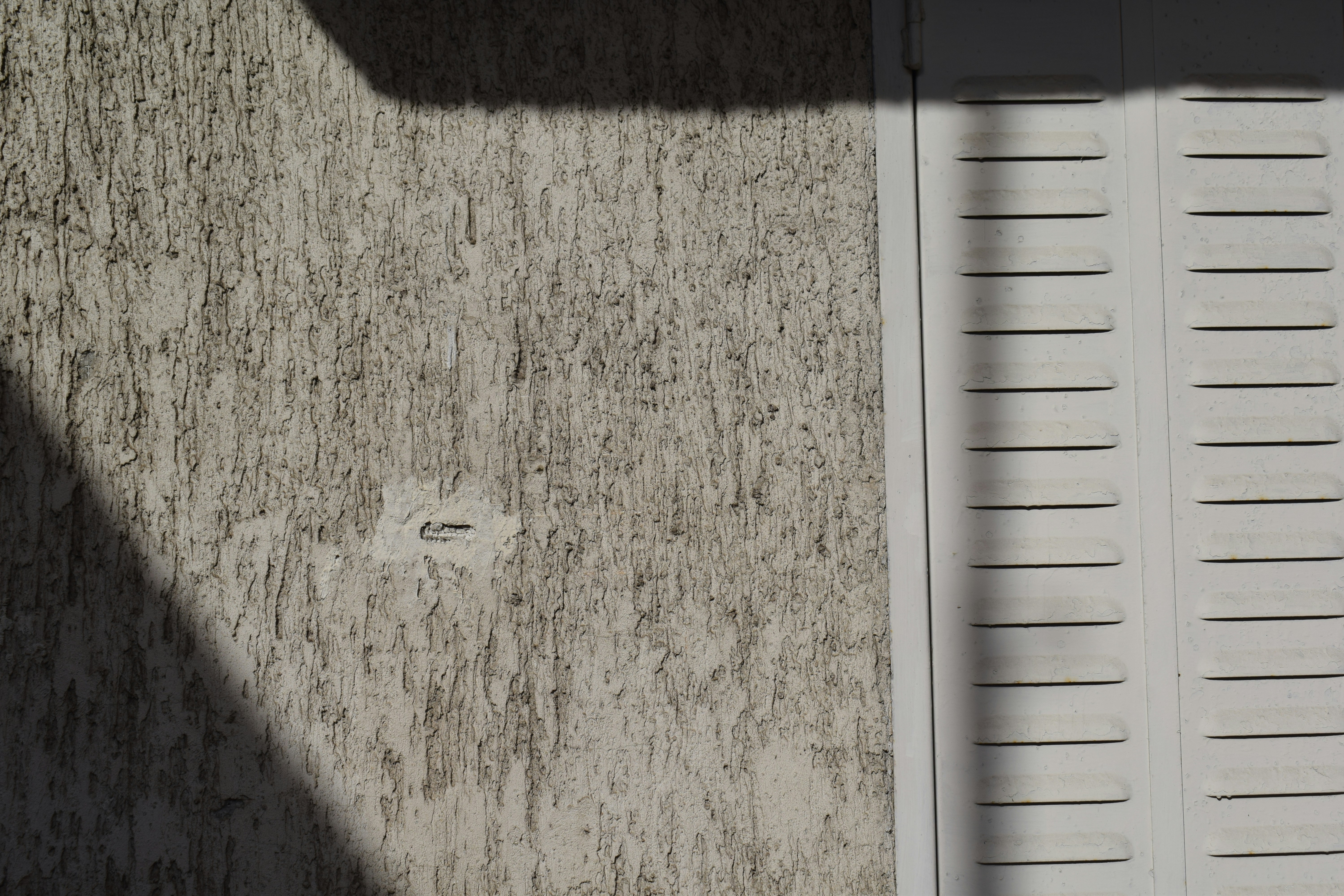 Mur texturé avec obturateur blanc et ombres.