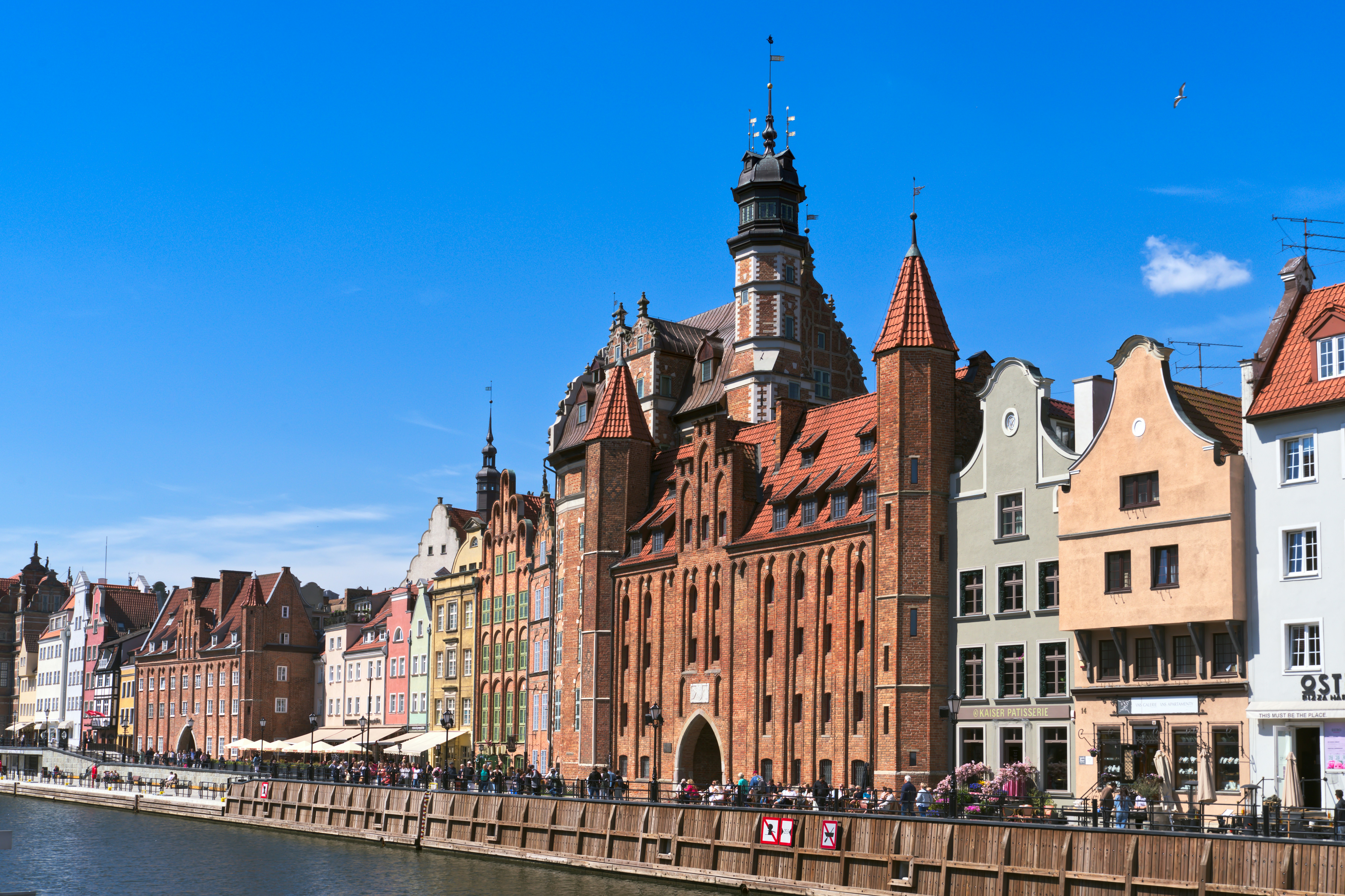 Des bâtiments historiques colorés bordent un front de mer sous un ciel bleu.